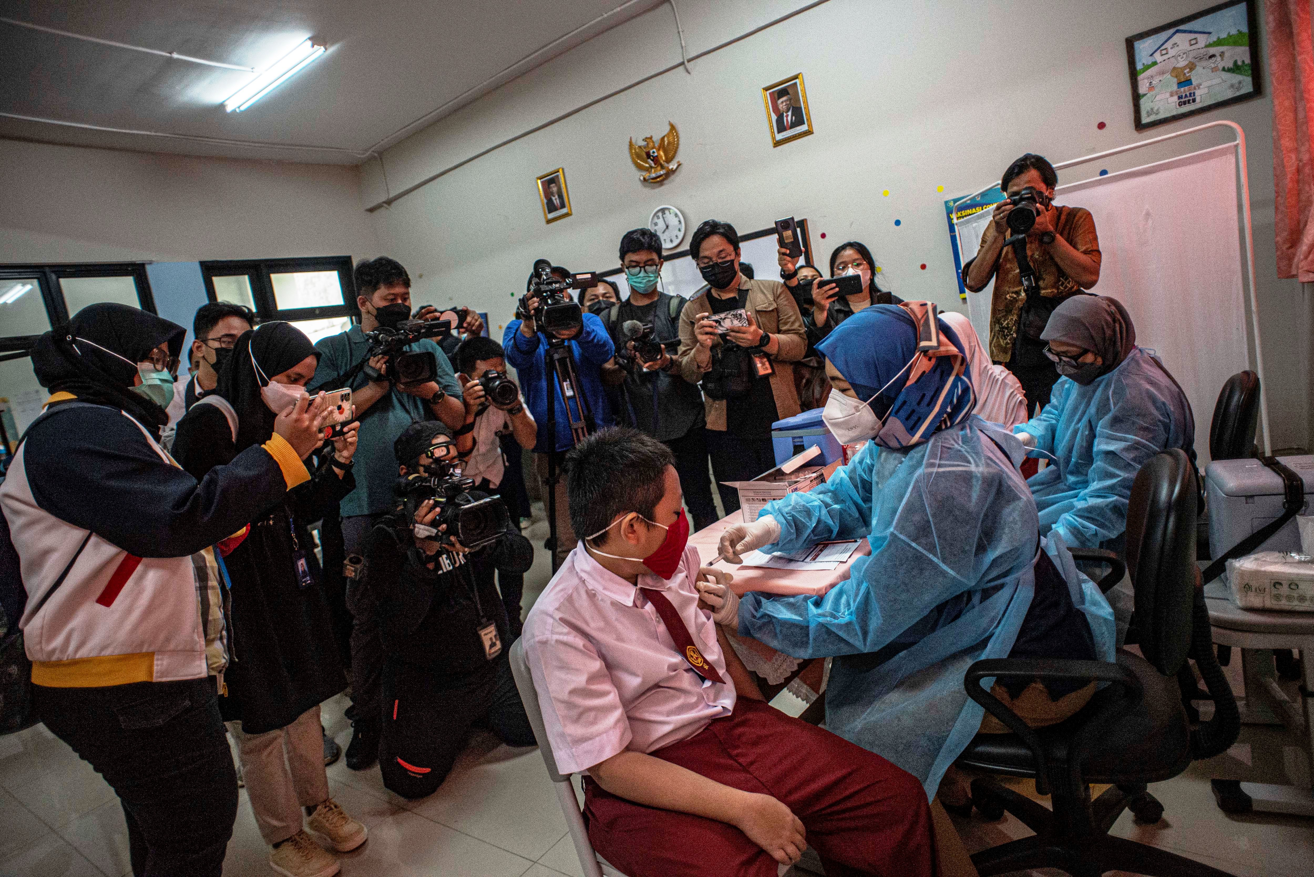 Tenaga kesehatan (kanan) menyuntikkan vaksin Covid-19 kepada pelajar di SDN Cempaka Putih Timur 03, Jakarta, Selasa (14/12).