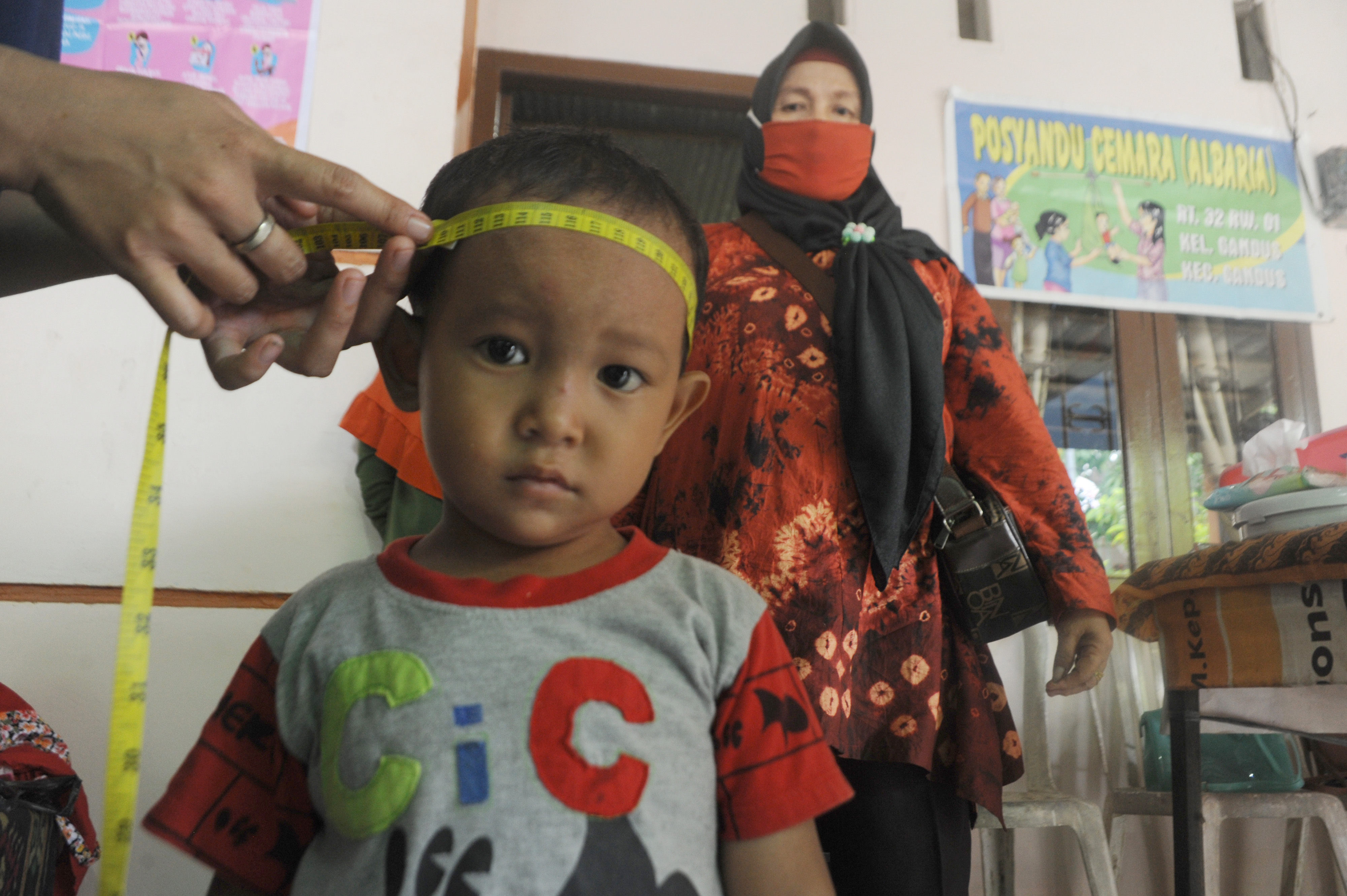Tenaga kesehatan mengukur lingjkar kepala anak untuk mendeteksi stunting