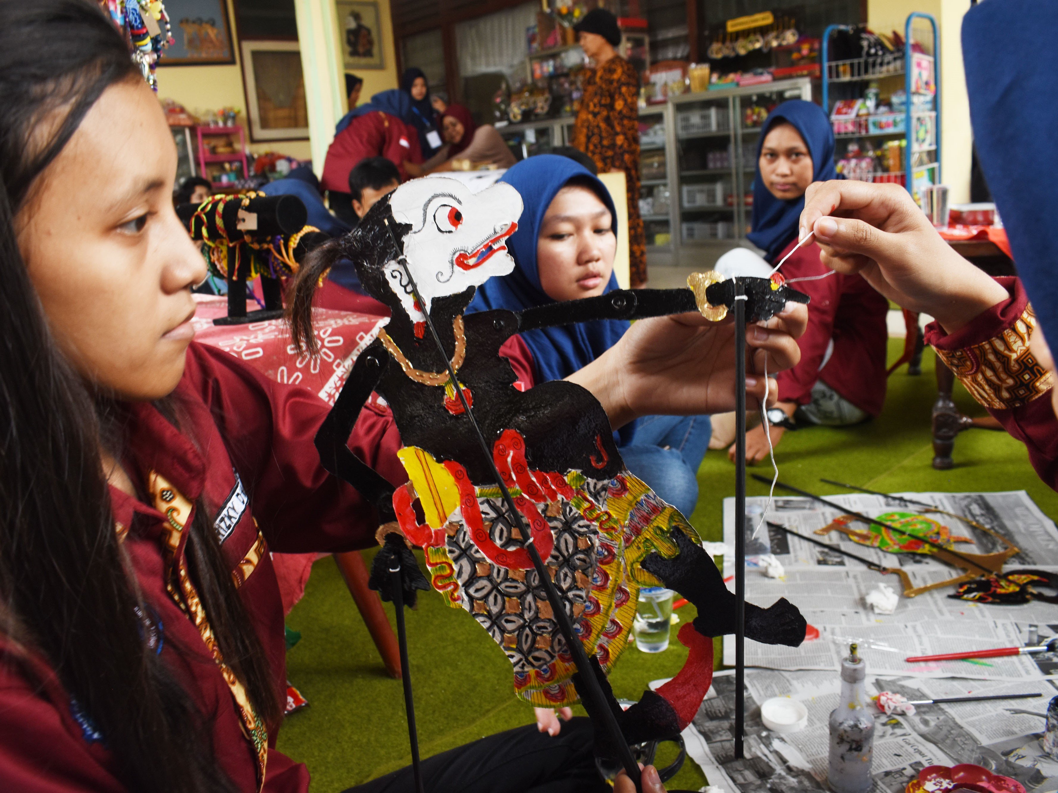 Mahasiswa menyelesaikan pembuatan wayang kulit berbahan karton saat mengikuti praktik kewirausahaan di tempat kerajinan wayang kulit.