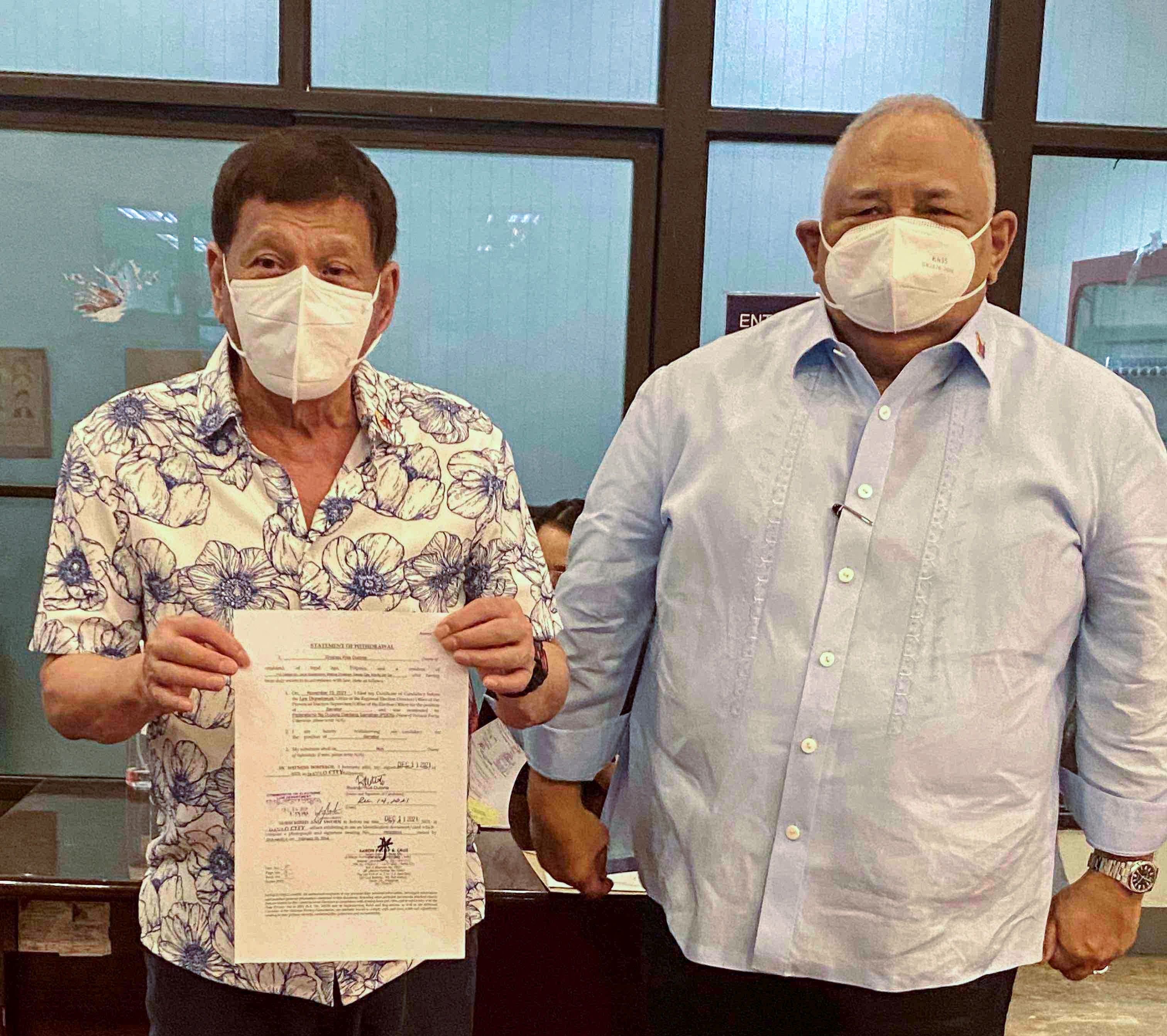 Presiden Rodrigo Duterte (kiri) menunjukkan dokumen penarikan dirinya sebagai calon senate pada pemilu Mei 2022. 