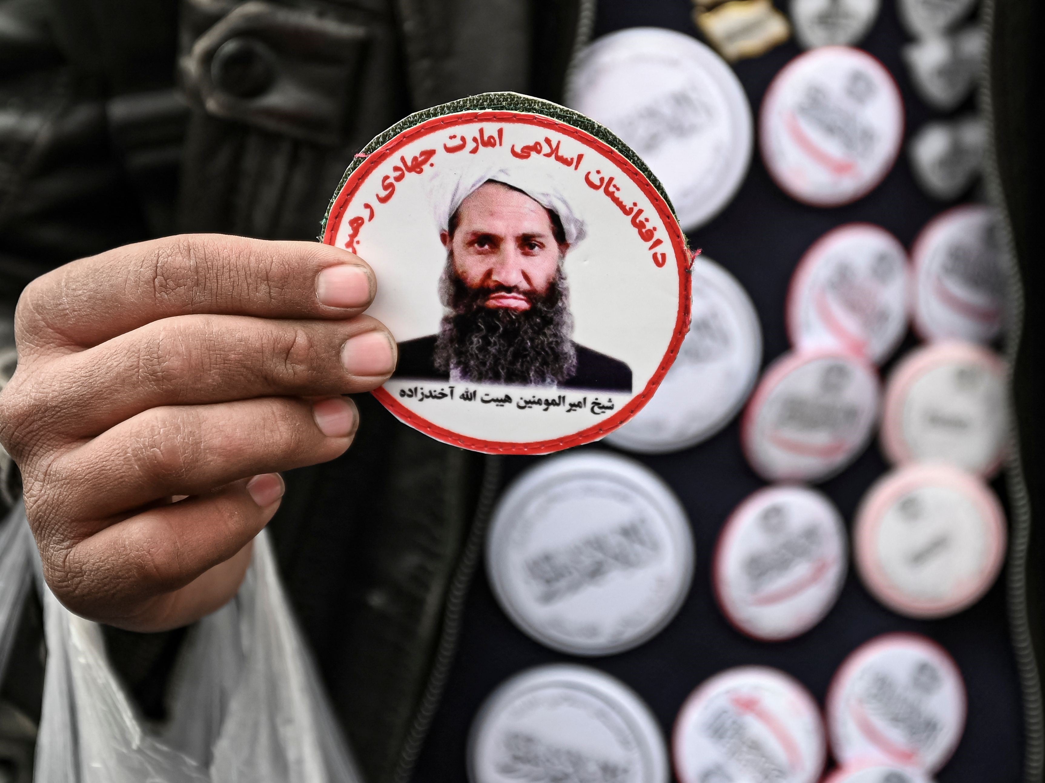 Seorang pria menjual stiker bergambar pemimpin tertinggi Taliban Haibatullah Akhundzada di pasar di Kabul pada 26 Desember 2021.