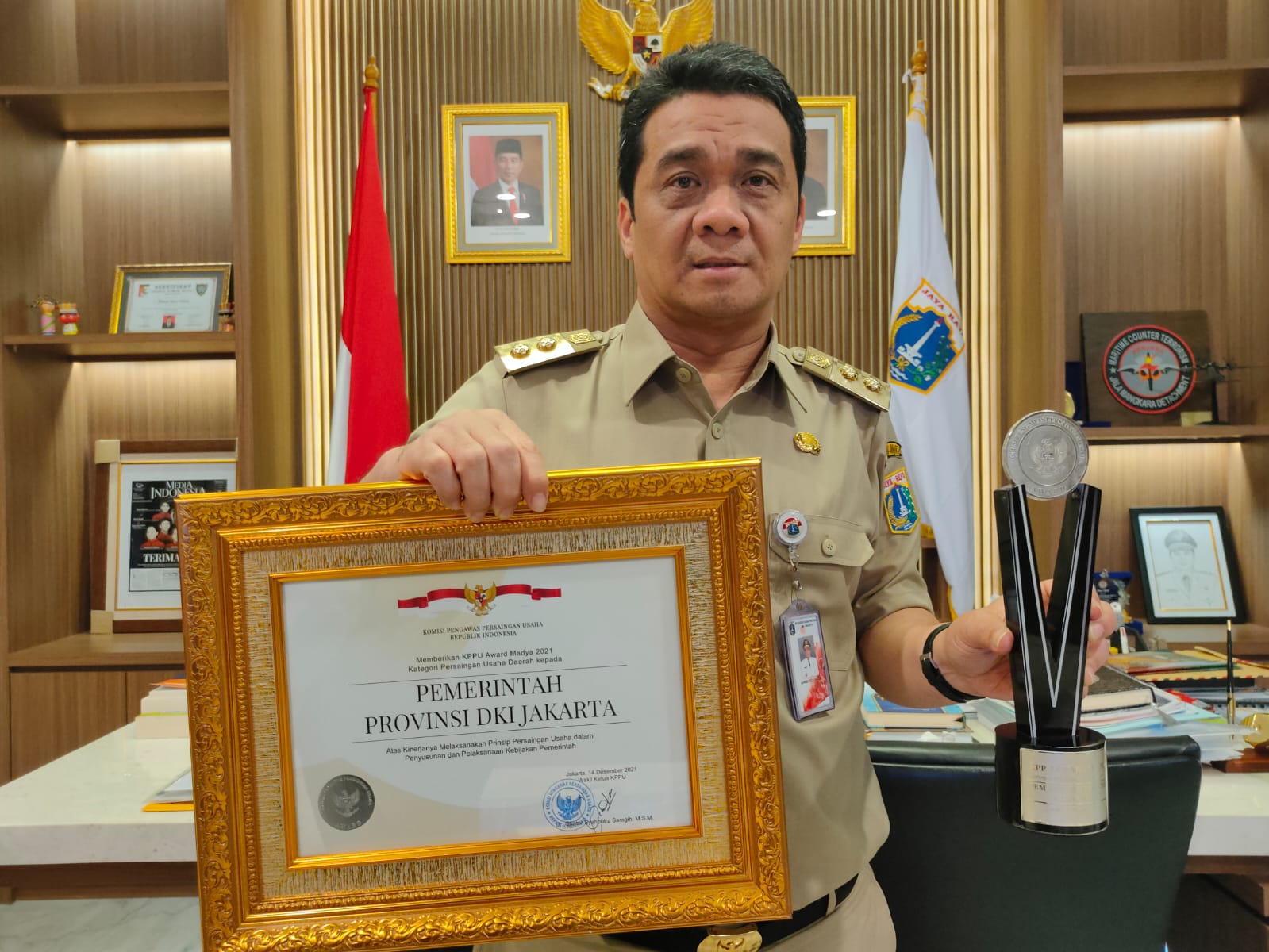 Wakil Gubernur DKI Jakarta, Ahmad Riza Patria, memperlihatkan piagam penghargaan dari KPPU, Kamis (16/12)