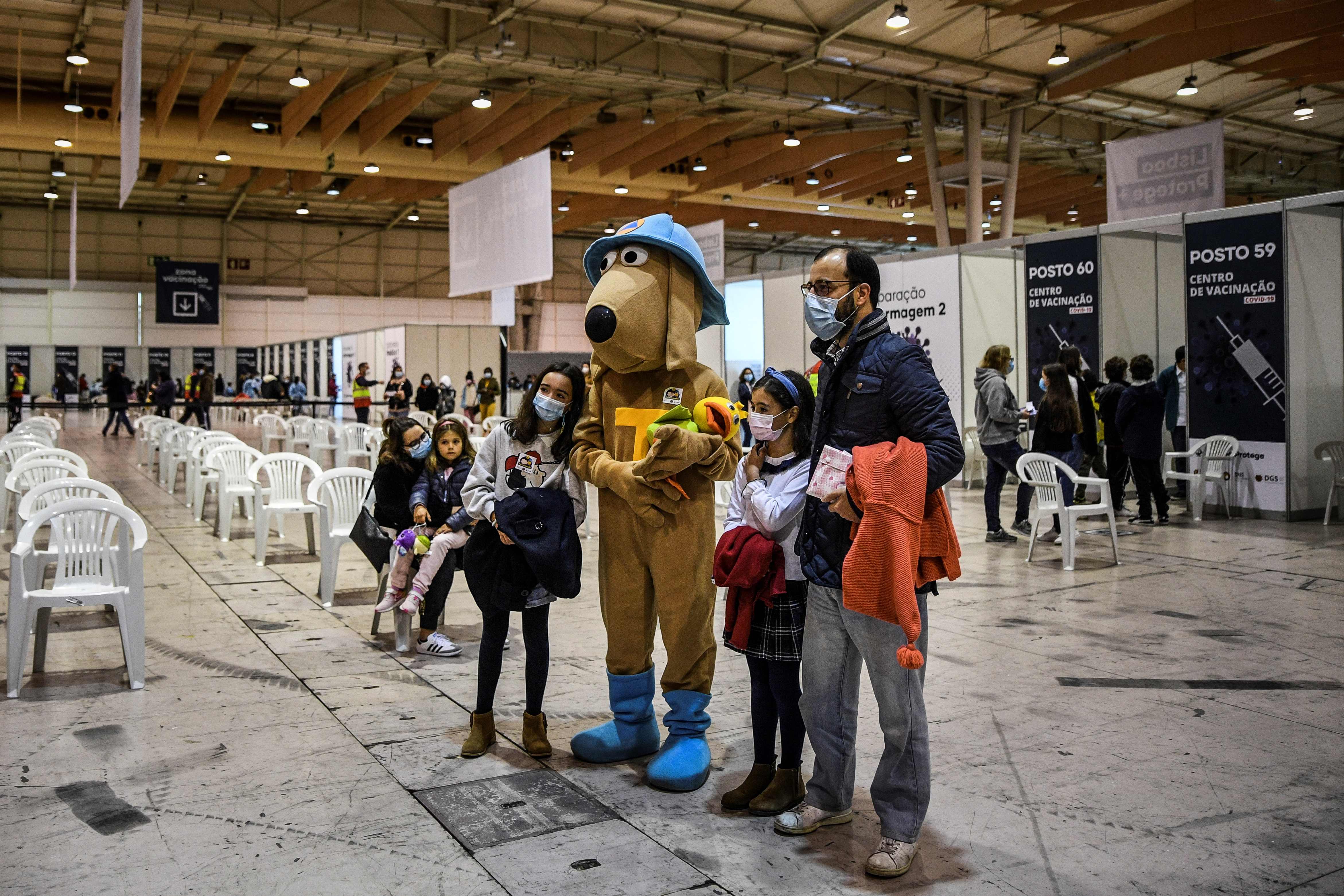 Anak-anak berpose dengan sebuah maskot setelah menerima vaksin covid-19 di Lisabon, Portugal.