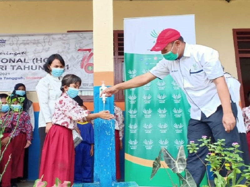 Seorang pelajar mencuci tangan dengan air mengalir dari fasilitas yang dibangun Asian Agri