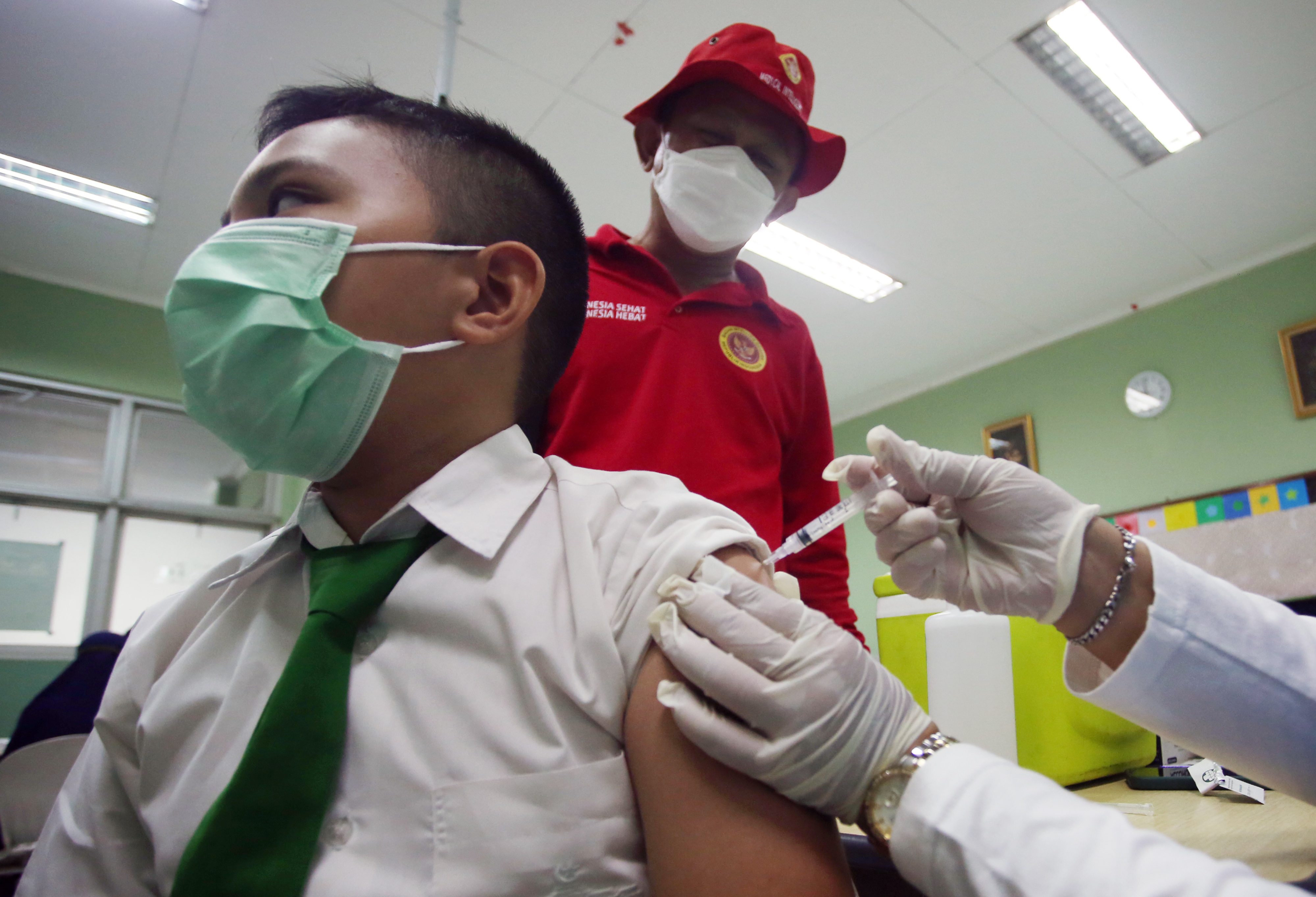 etugas kesehatan menyuntikan vaksin covid-19 dosis pertama pada siswa di SD Al Azhar, Serpong, Tangerang Selatan, Banten, Rabu (15/12/2021)