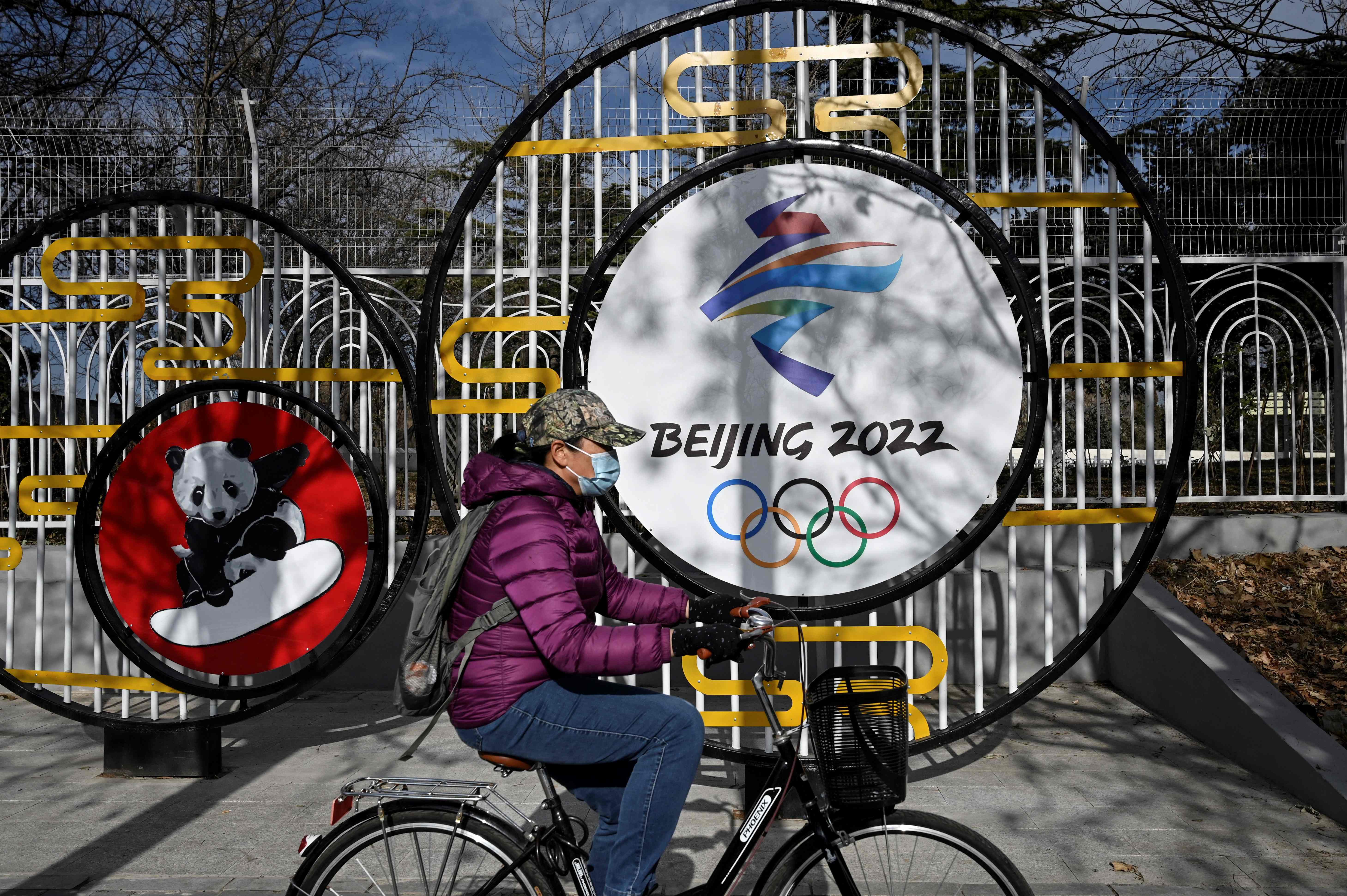 Seorang warga melintas di depan logo Olimpiade Beijing 2022 di Beijing, Tiongkok.