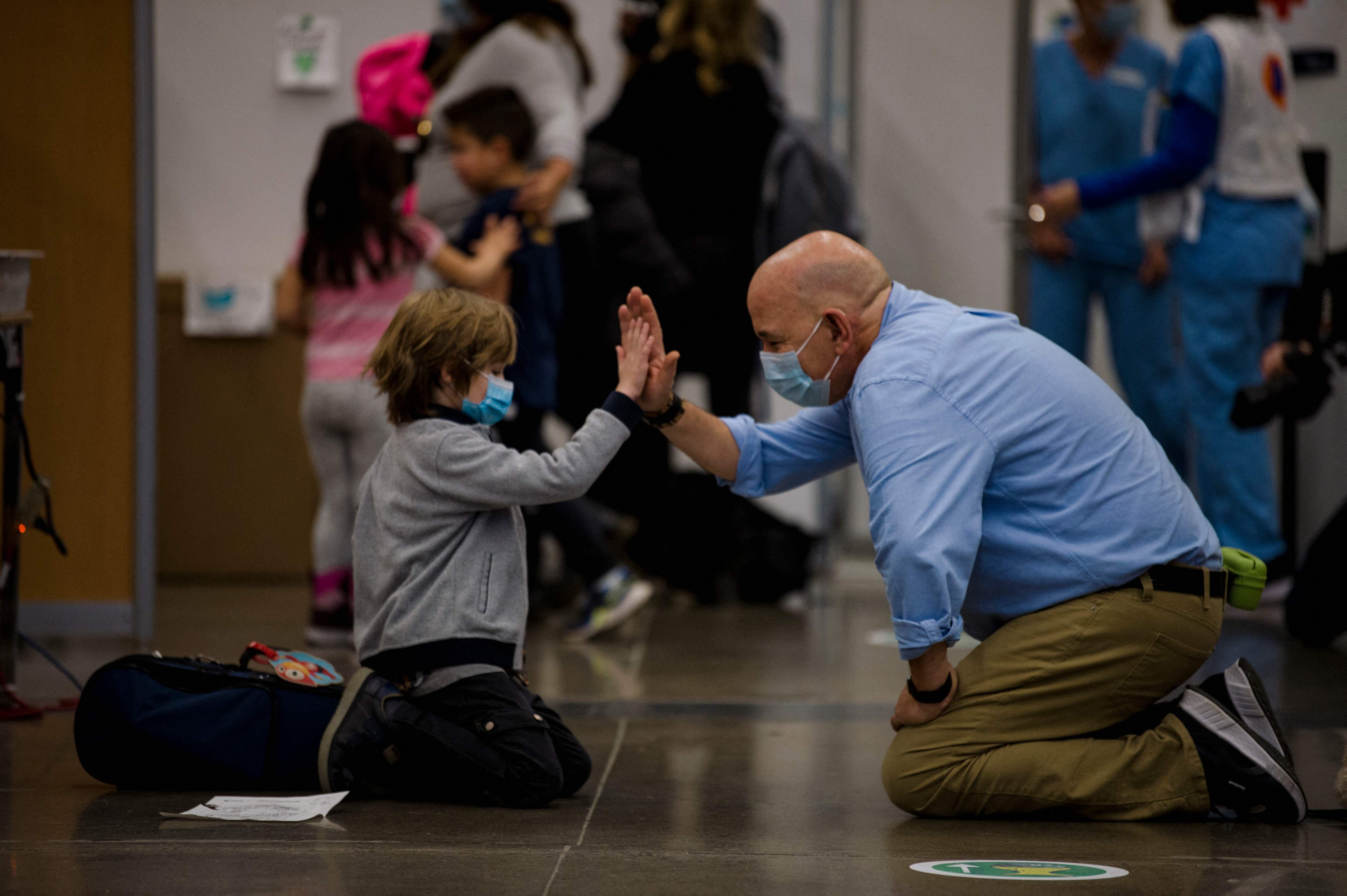 Petugas medis memberi salam tepuk kepada anak yang hendak divaksin Covid-19 Pfizer-BioNTech di Montreal, Quebec, Kanada. 