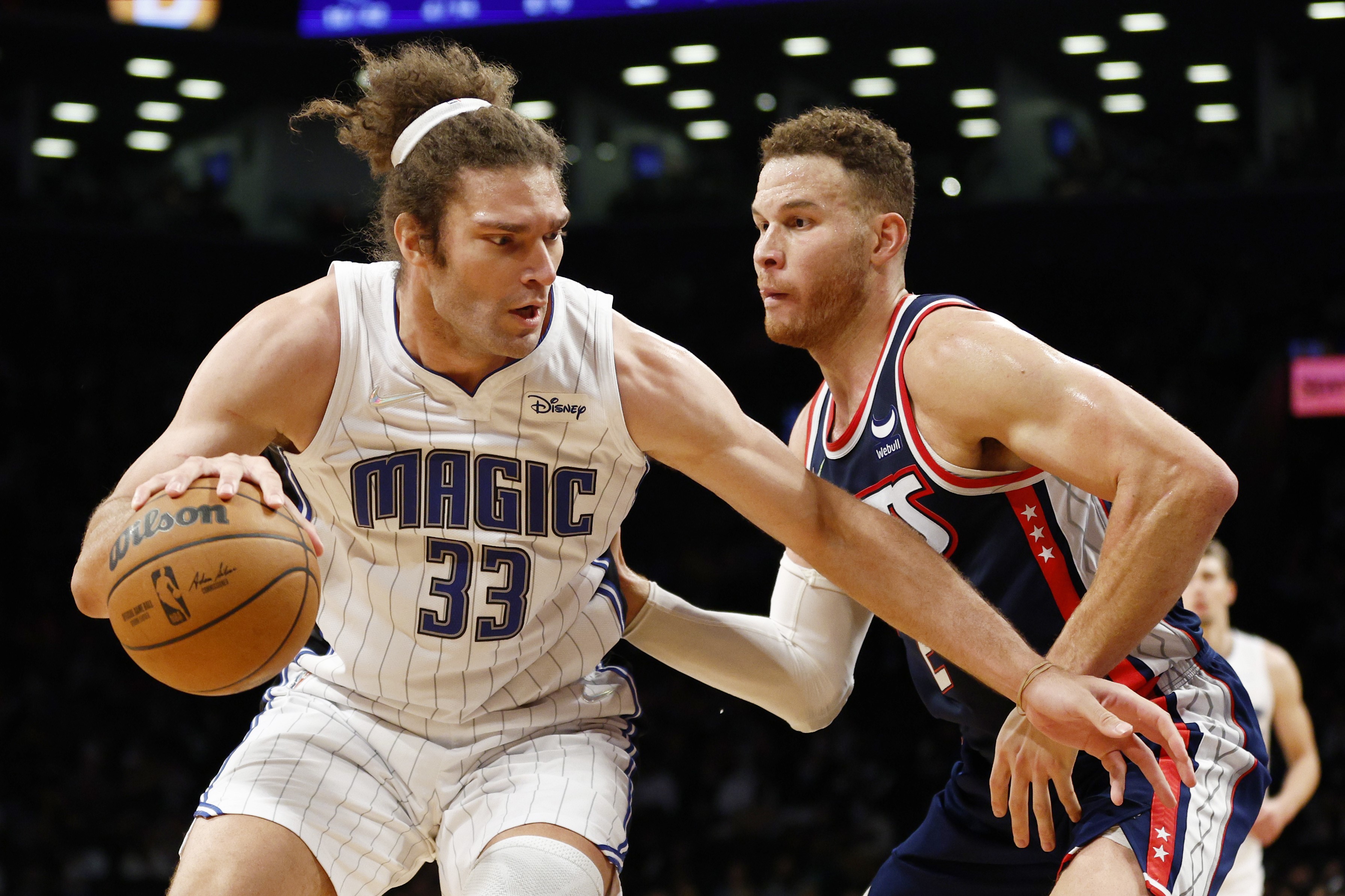 Pemain Orlando Magic Robin Lopez (kiri) menggiring bola semantera itu Blake Griffin dari Brooklyn Nets mencoba untuk menghalangi.