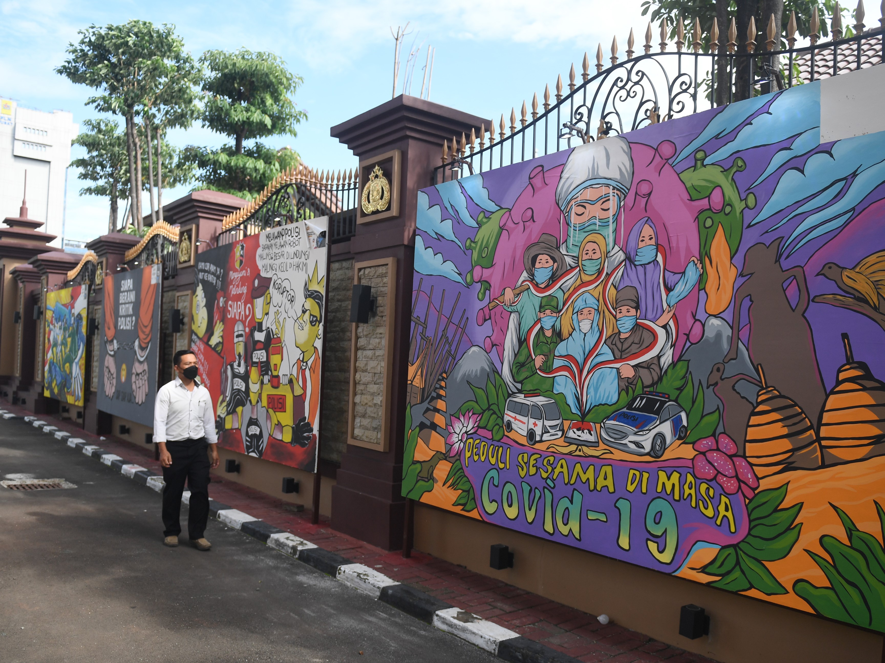 Warga melintas di dekat mural bertema covid-19 di Jakarta, Rabu (1/12/2021). 