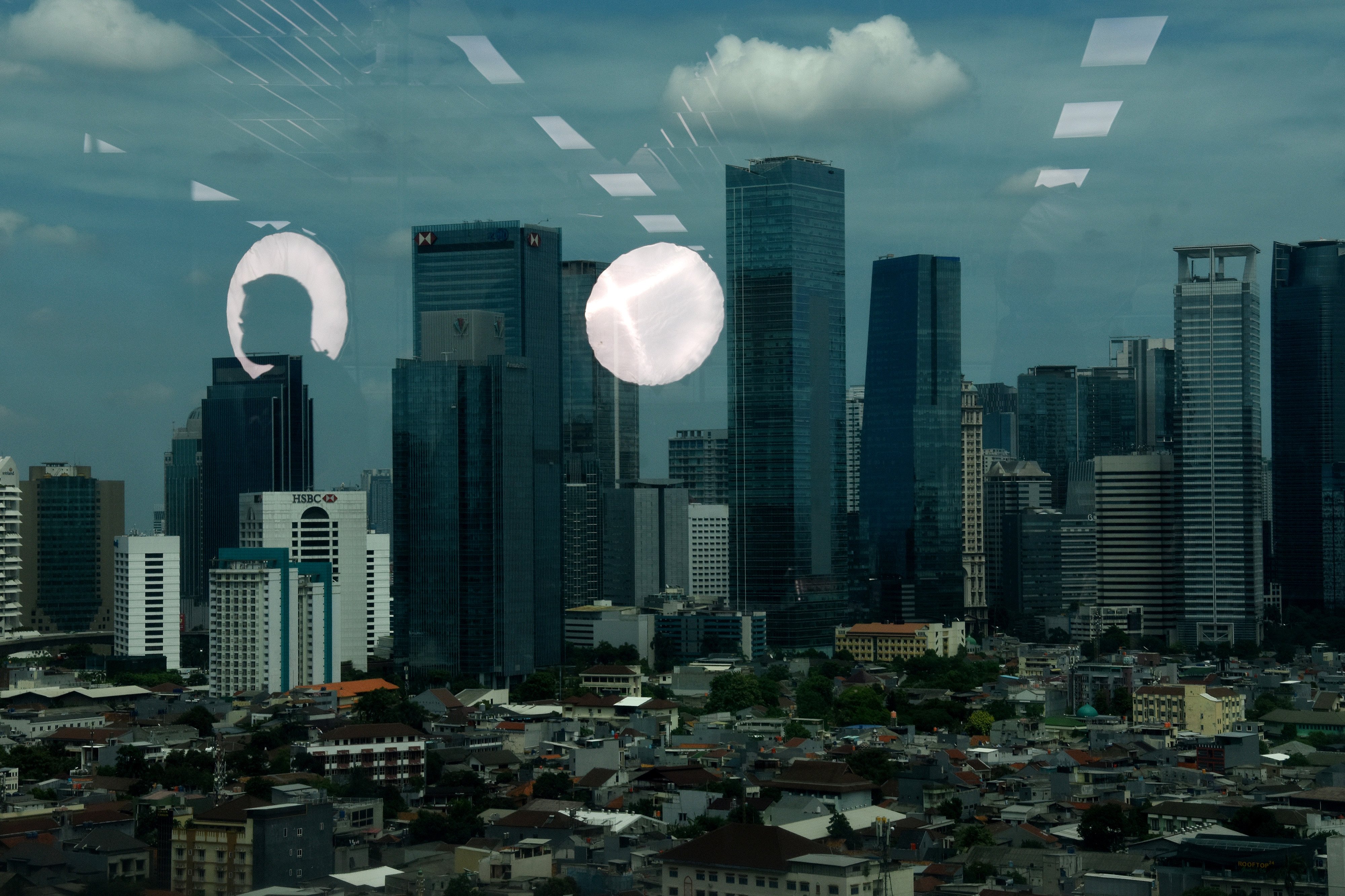 TREN PENDUDUK MENINGKAT: Bayangan seorang pekerja beraktifitas di kantornya dengan latar deretan permukiman penduduk di Jakarta.