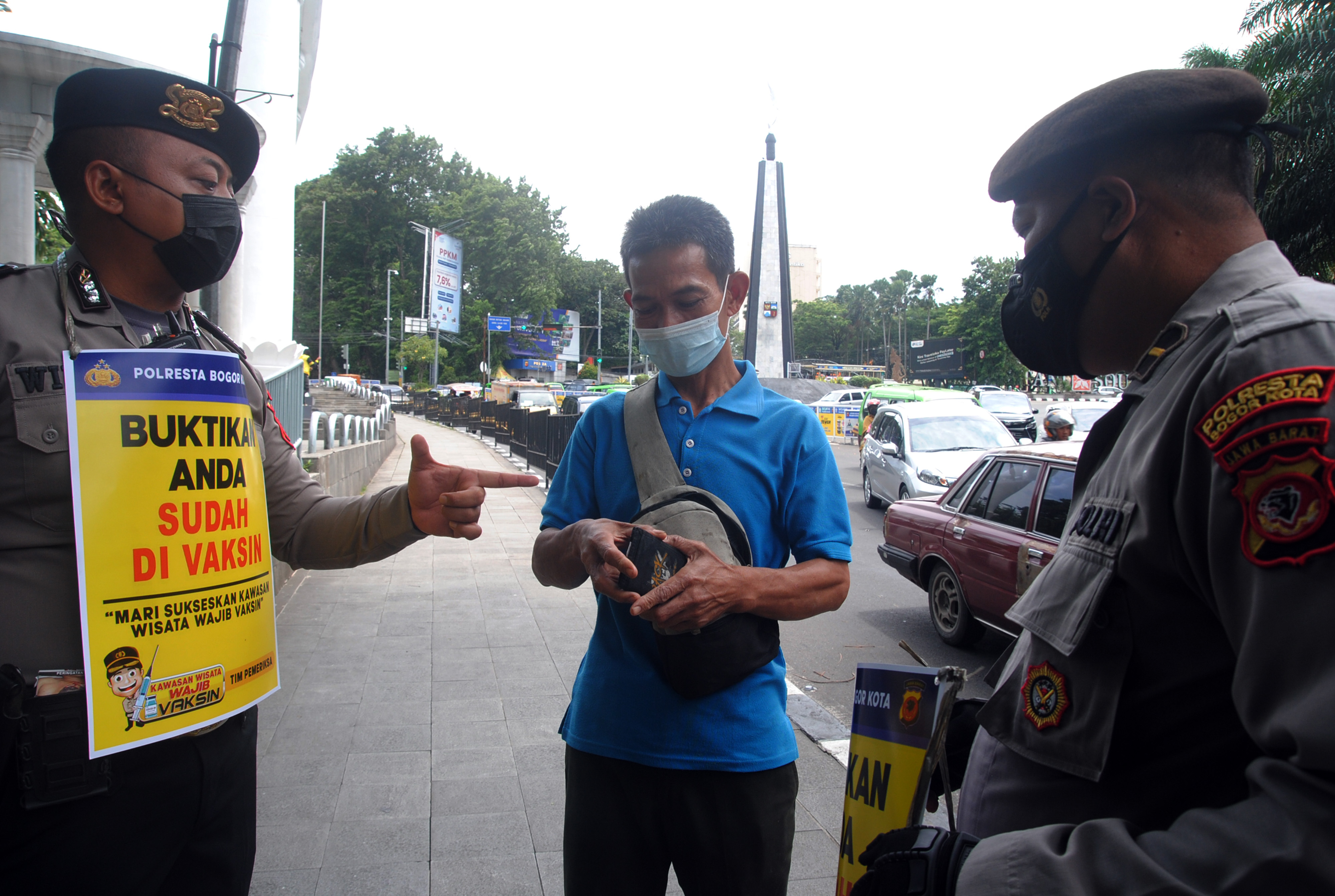 Anggota Polresta Bogor Kota memeriksa bukti vaksin warga di kawasan Pedestrian Kebun Raya Bogor, Jawa Barat.