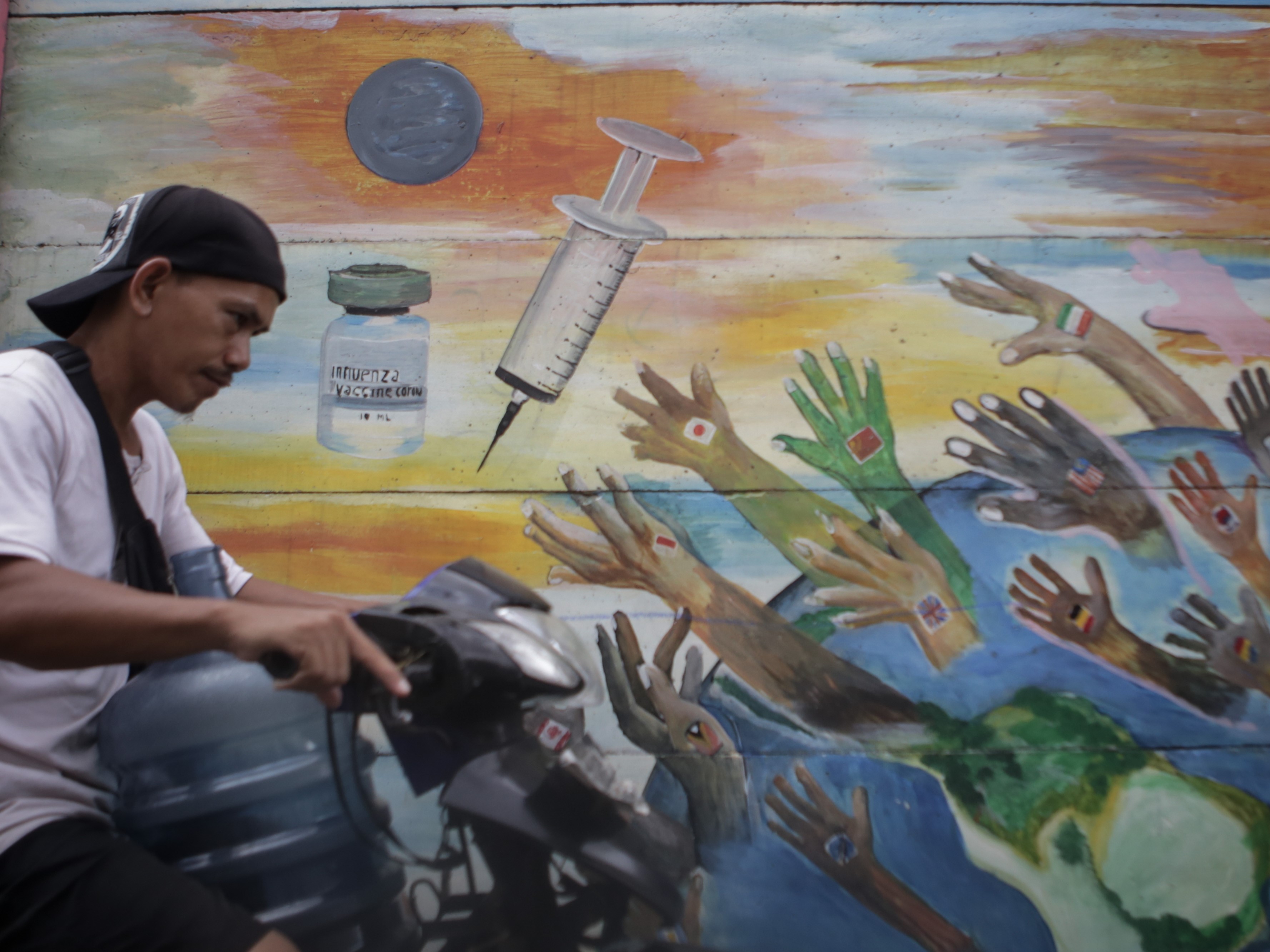 Warga melintas di depan mural bertema vaksin covid-19 di Tanah Tinggi, di Kota Tangerang, Banten, Senin (22/11/2021).