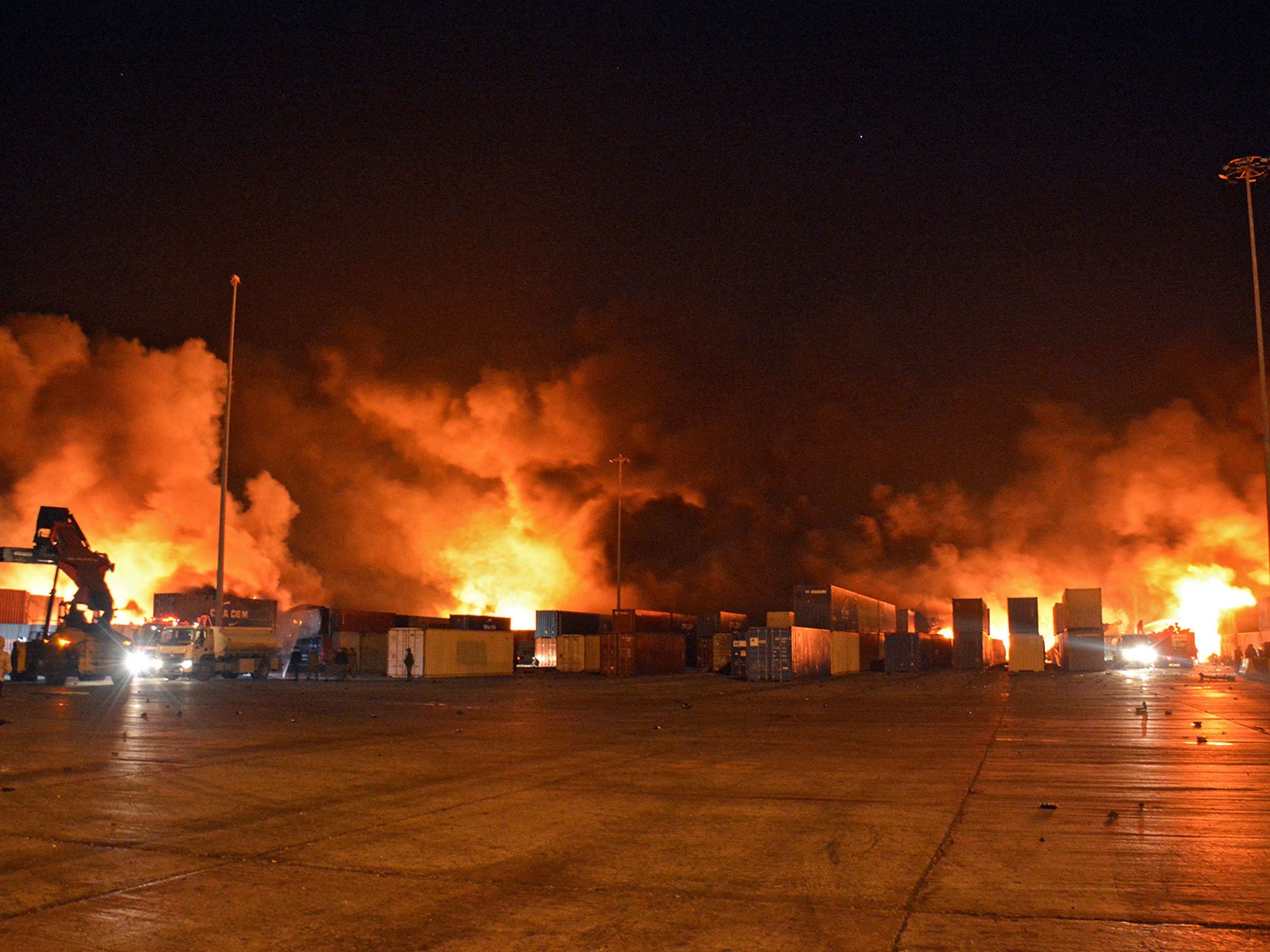 Petugas pemadam kebakaran berjuang melawan kobaran api di pelabuhan Latakia Suriah setelah serangan udara Israel pada 28 Desember 2021.
