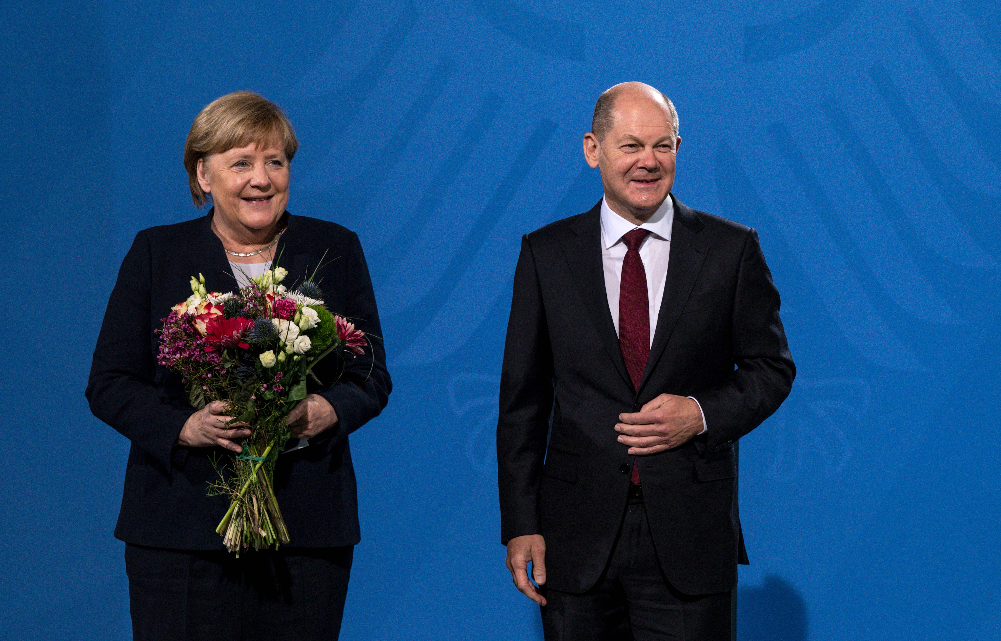Kanselir Jerman yang baru terpilih Olaf Scholz (kanan) and pejabat yang digantikannya, Angela Merkel, saat serah terima jabatan di Berlin.