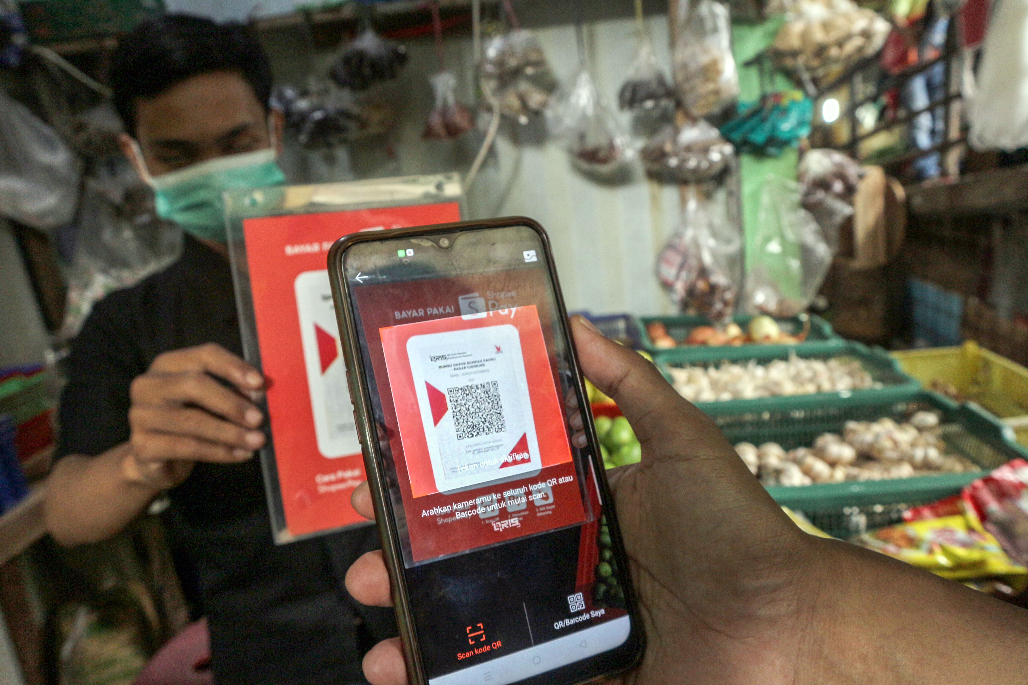 Warga bertransaksi digital menggunakan QRIS saat berbelanja di Pasar Tradisional Cibinong, Kabupaten Bogor, Jawa Barat.