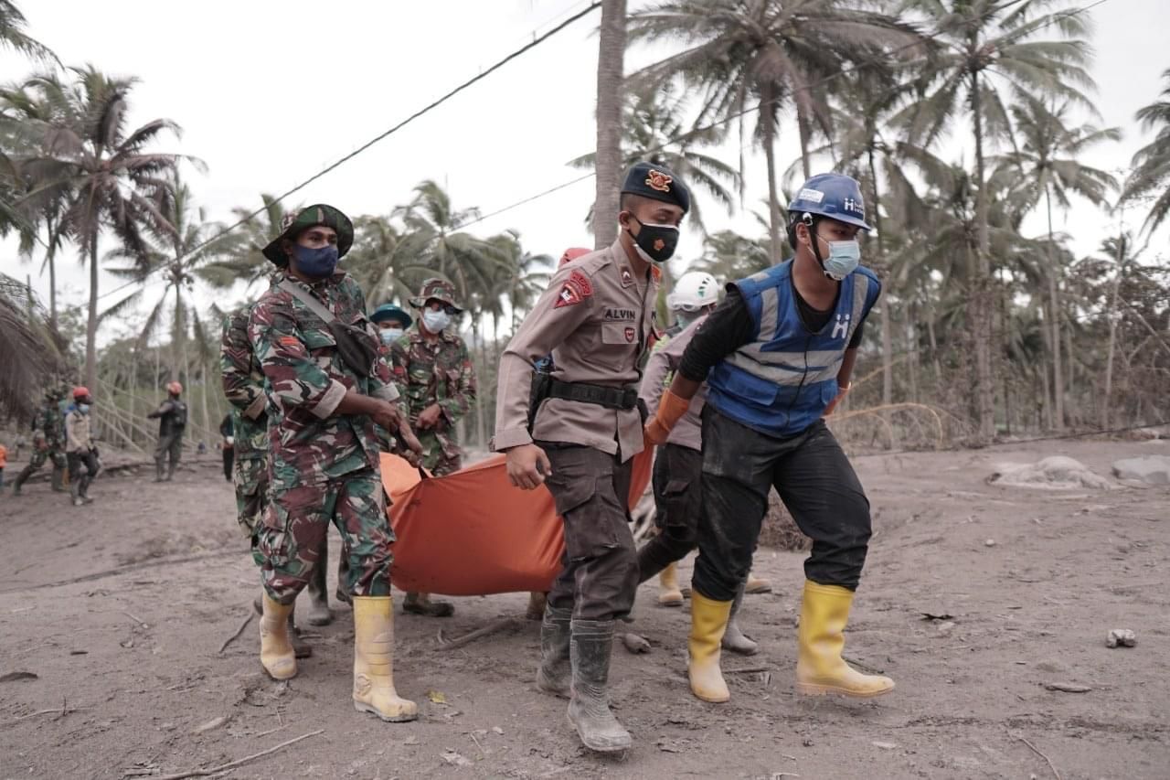 Anggota tim Human Initiative (kanan) bersama aparat Polri dan TNI membawa jenazah korban erupsi Gunung Semeru.