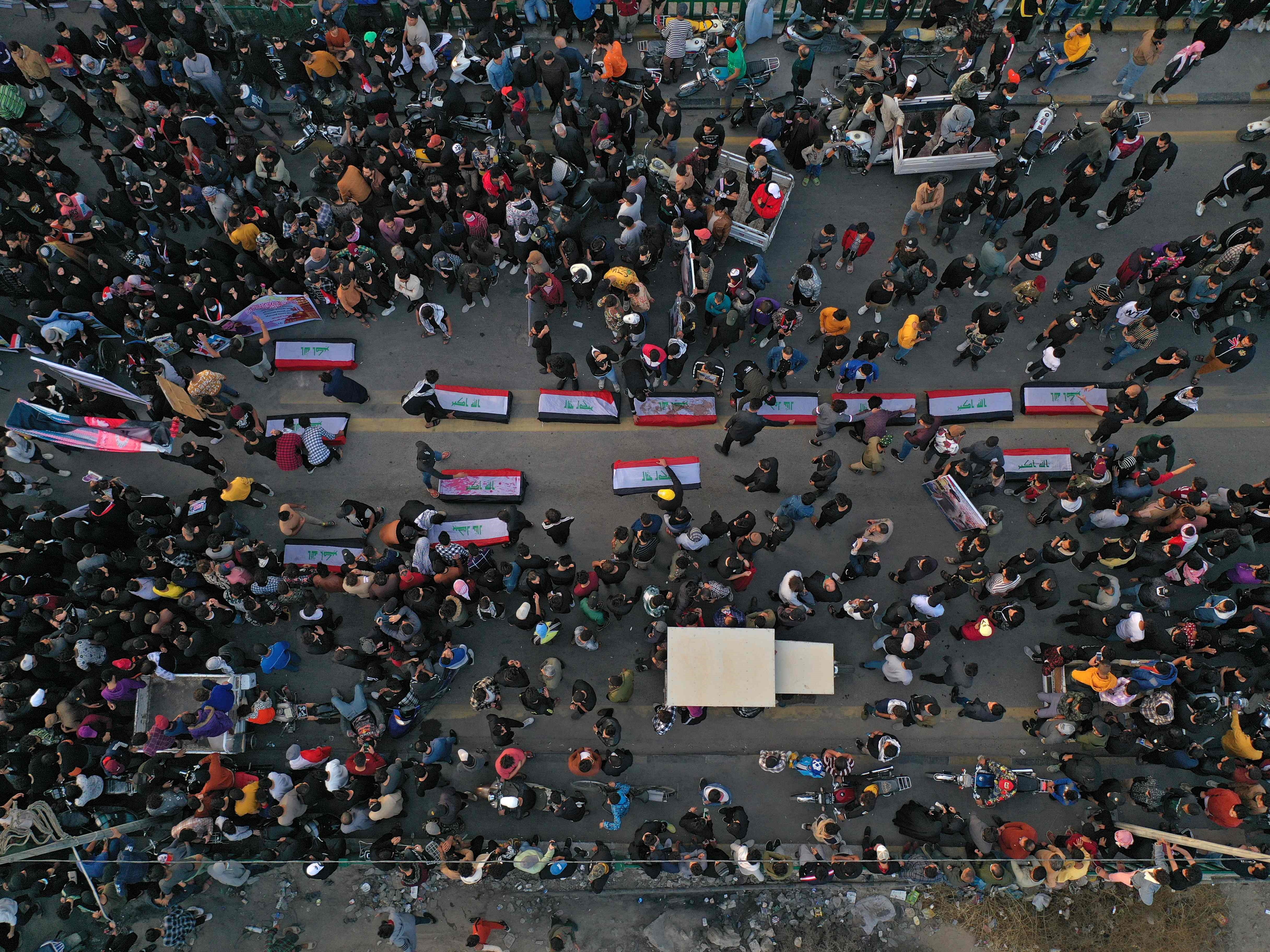 warga Irak membawa poster pengunjuk rasa antipemerintah yang terbunuh paad 2019 dalam acara peringatannya di kota Nasiriyah, akhir November.