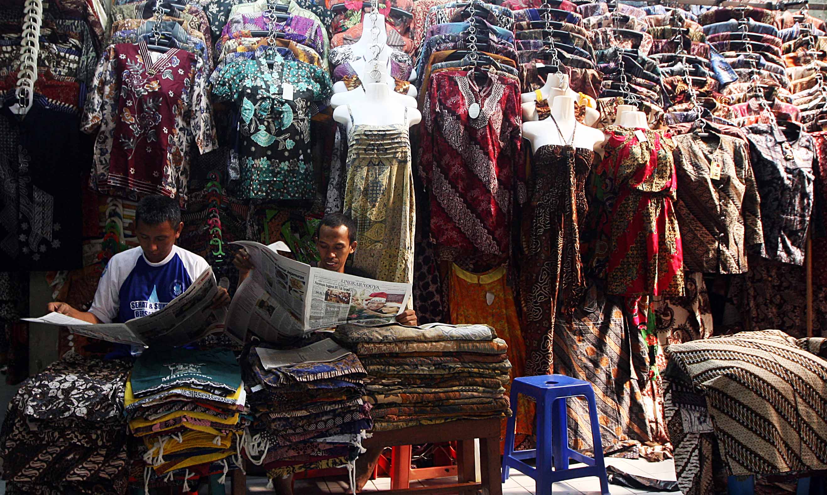  Pedagang batik membaca koran saat menunggu pembeli di Pasar Beringharjo, Malioboro, Yogyakarta, beberapa waktu lalu.