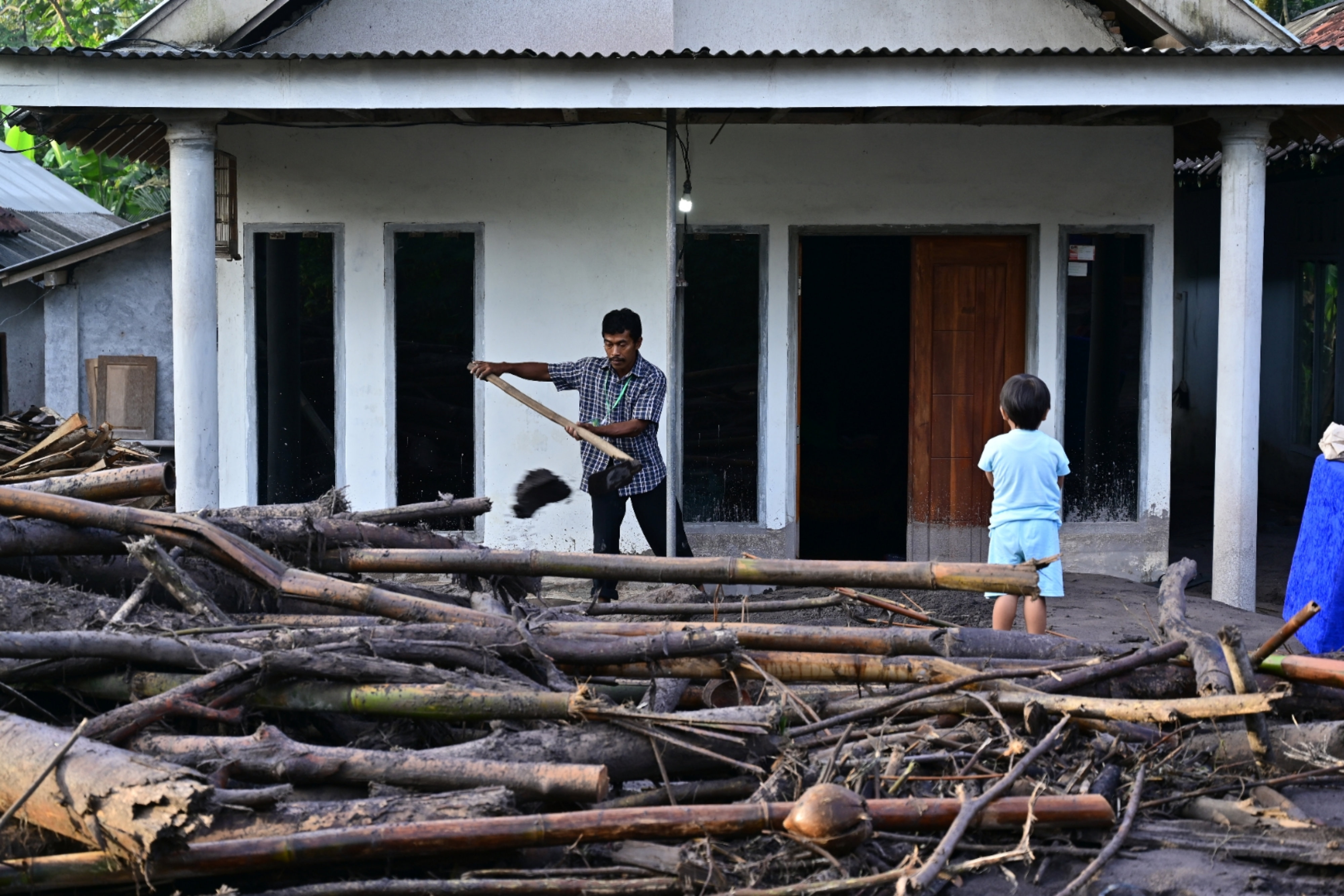 Warga membersihkan material lahar hujan Gunung Semeru yang masuk ke dalam rumahnya di Kebondeli Utara, Candipuro, Lumajang, Jawa Timur.