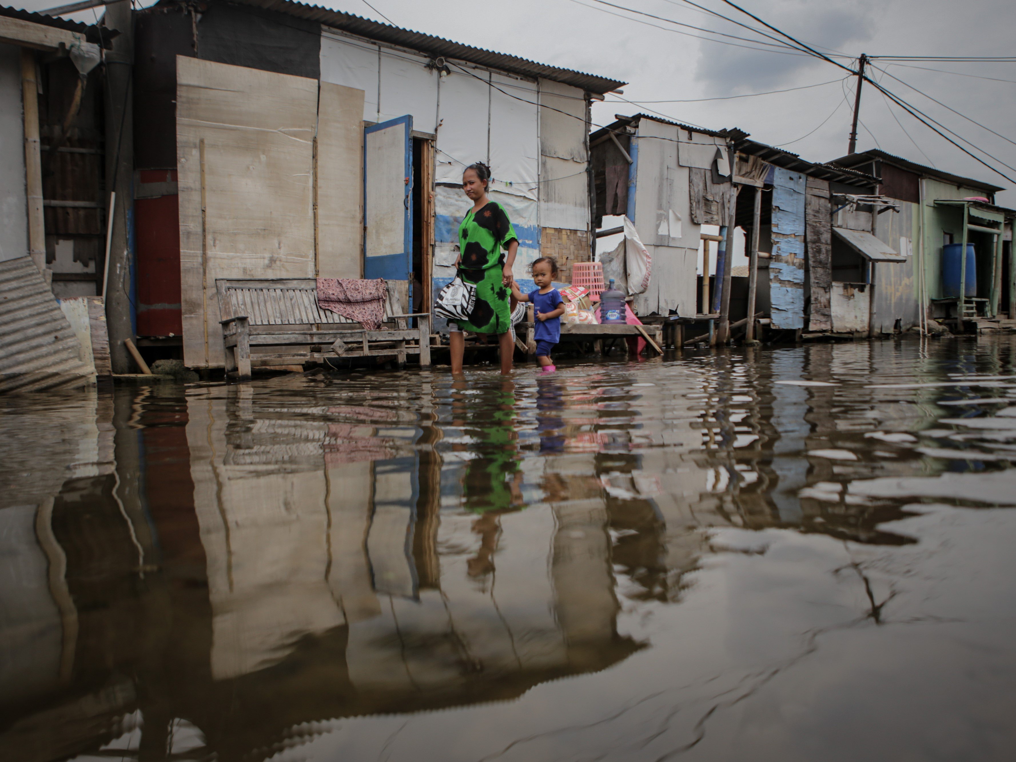 Warga berjalan di kawasan yang terkena banjir rob di Dadap, Kabupaten Tangerang, Banten, Jumat (12/11/2021).