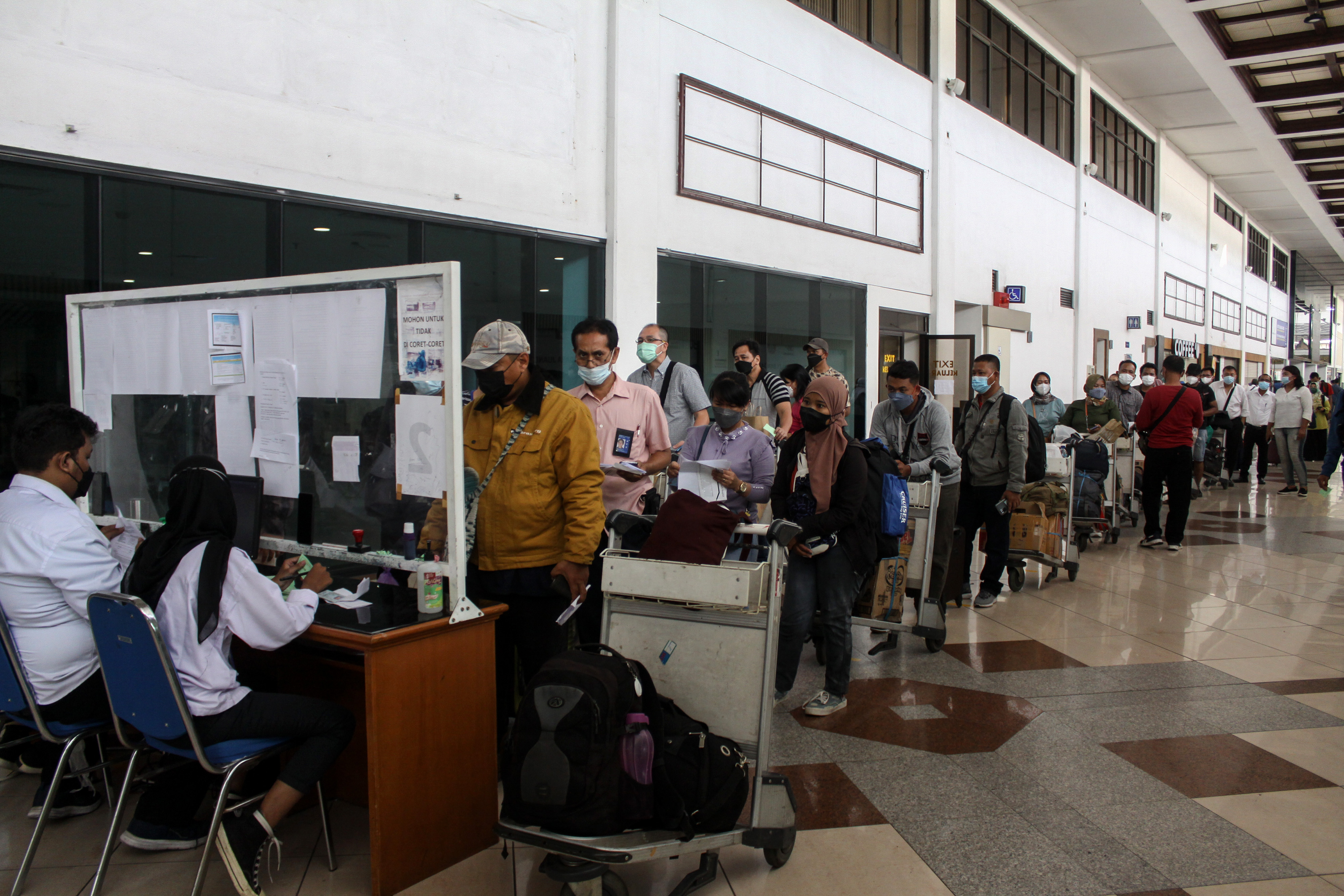 Penumpang pesawat menunjukkan syarat perjalanan ke petugas