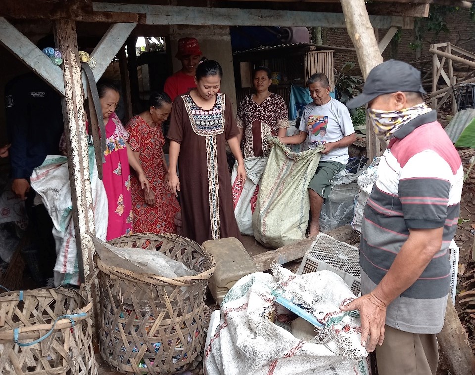 Pengepul barang bekas tengah memerhatikan proses pengepakan kaleng-kaleng bekas dengan alat bantuan UTA-45, di Desa Cipeucang, Kec. Cil 