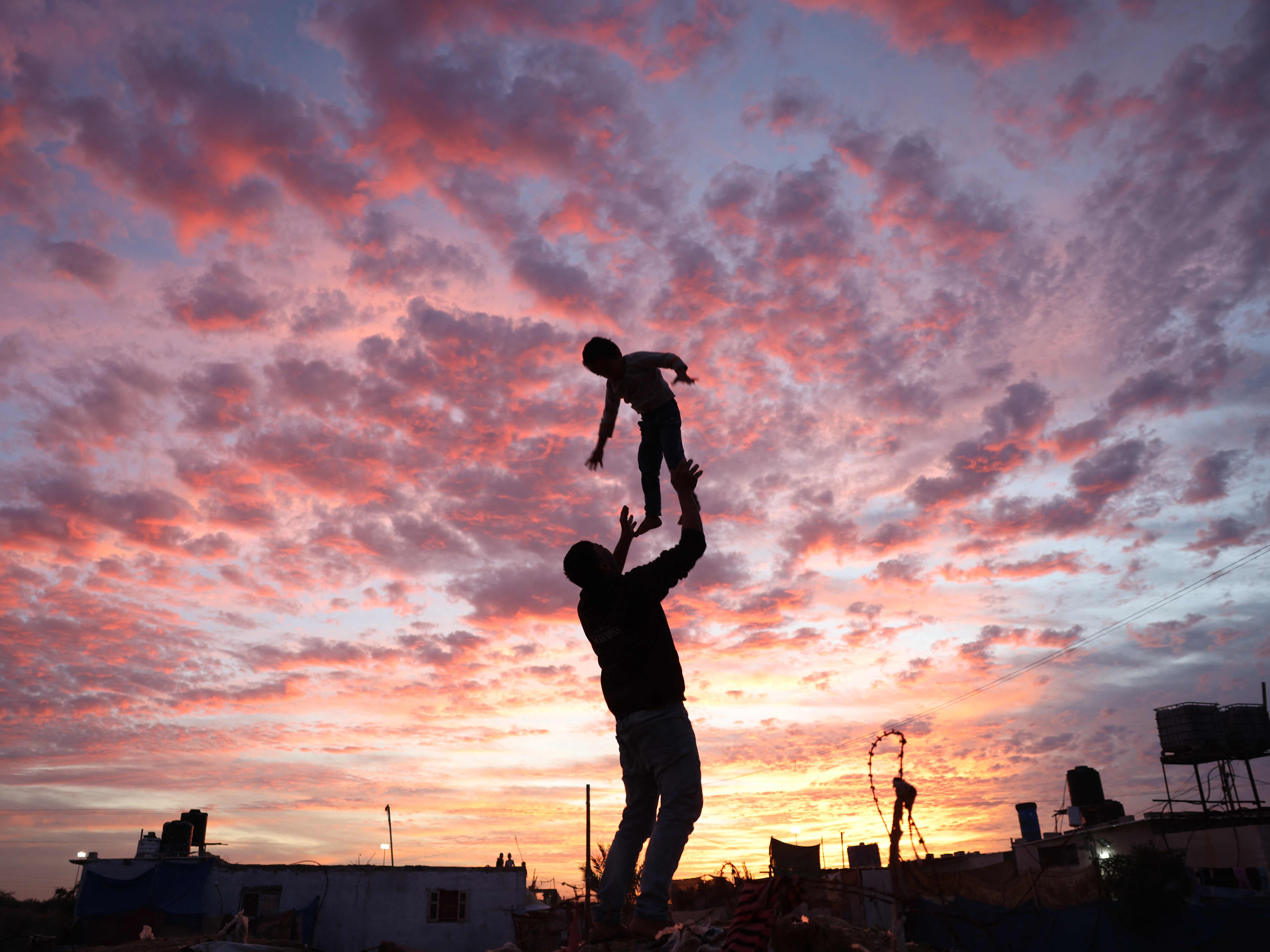 Seorang pria Palestina bermain dengan seorang anak saat matahari terbenam di Rafah di Jalur Gaza selatan pada 4 Desember 2021.