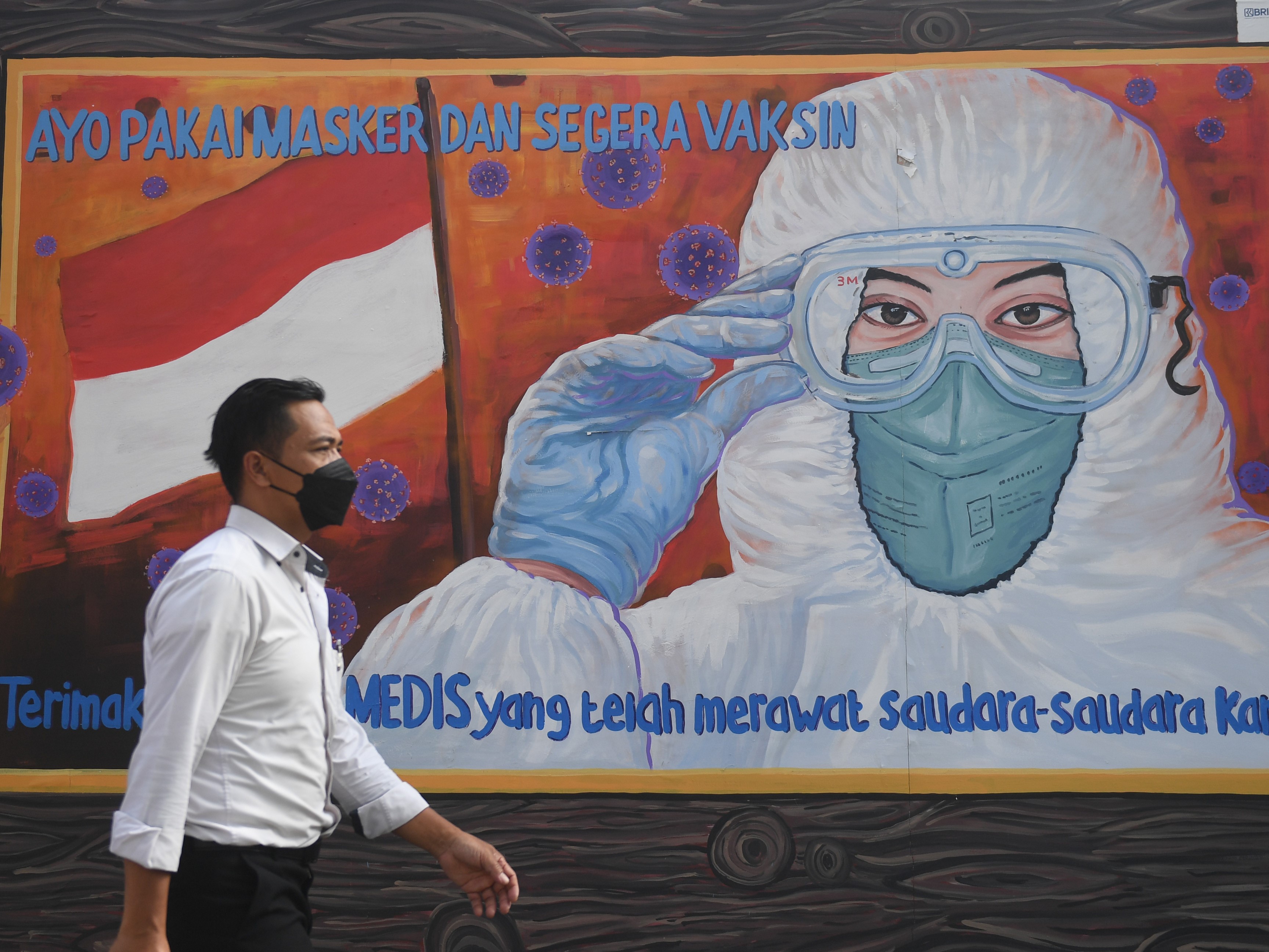 Warga melintas di dekat mural bertema covid-19 di Jakarta, Rabu (1/12/2021).