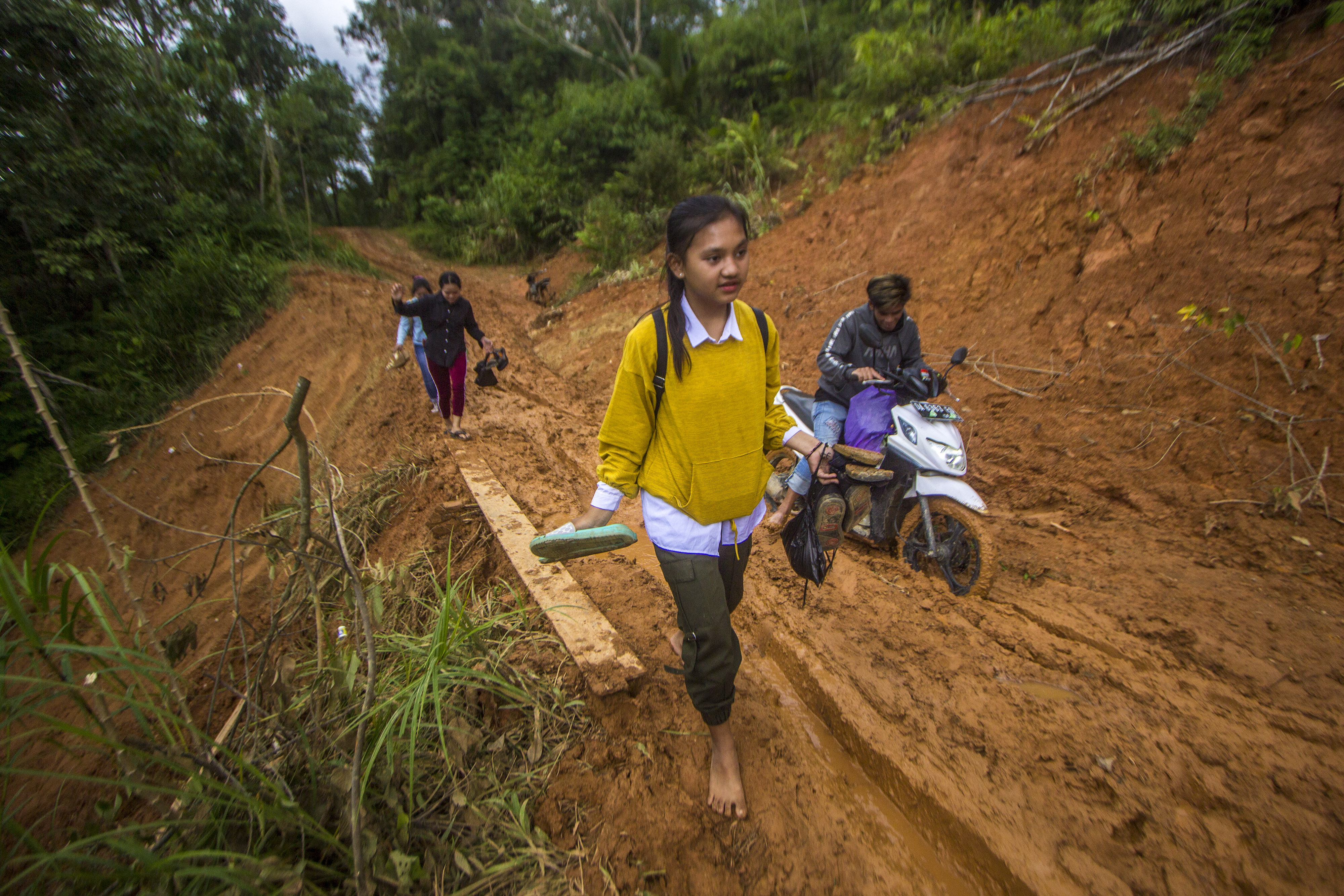 Warga berjalan melewati tanah longsor yang menutupi jalan antardesa di Desa Datar Ajab, Kabupaten Hulu Sungai Tengah, Kalimantan Selatan.