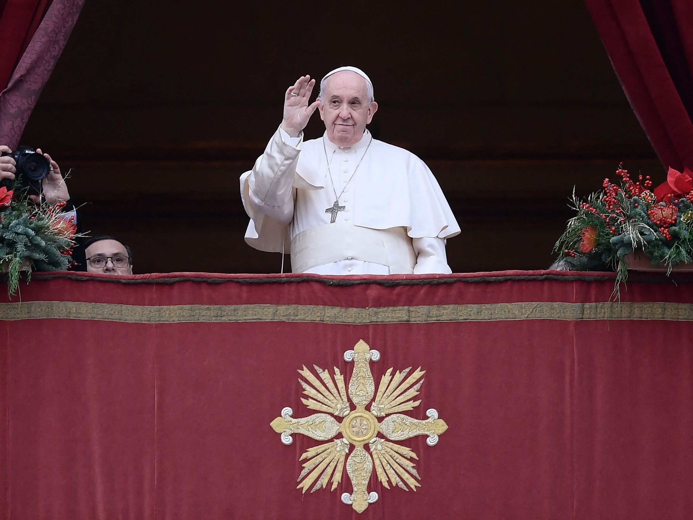 Paus Fransiskus melambai dari balkon sebelum memberikan berkat Natal Urbi et Orbi kepada umat beriman di Lapangan Santo Petrus.