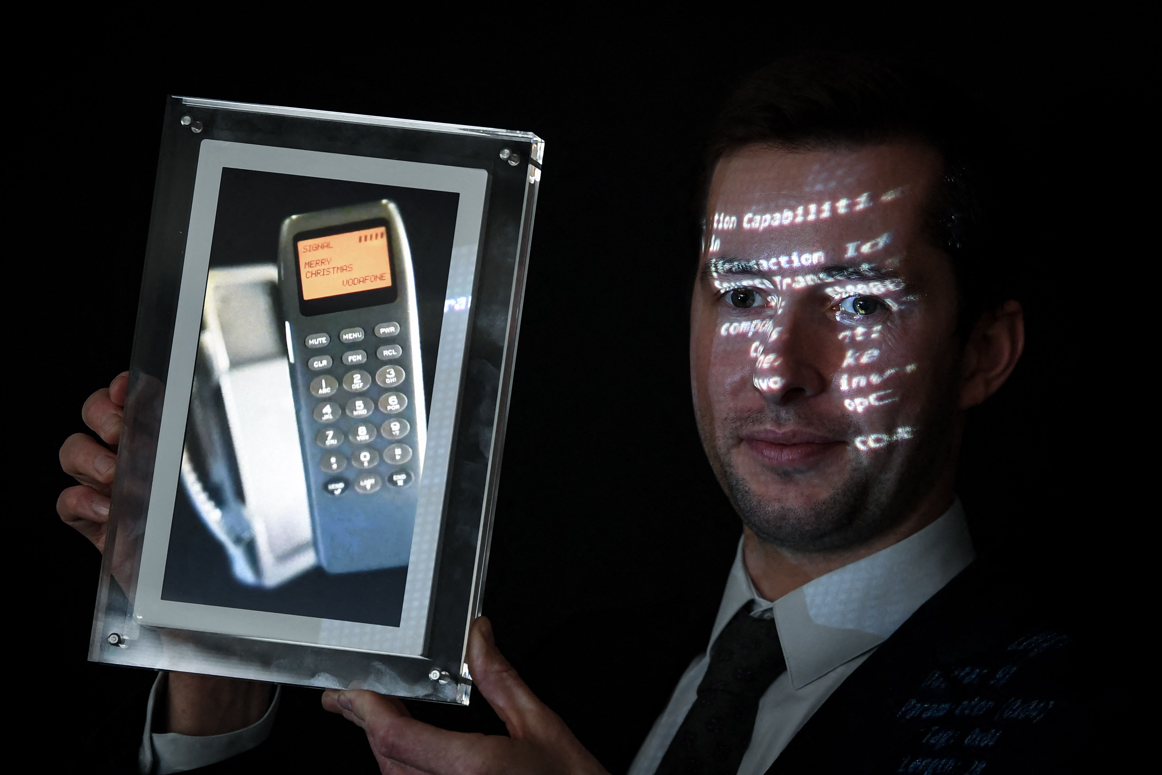 Petugas memegang foto telepon dengan SMS ucapan Selamat Natal pertama di dunia.