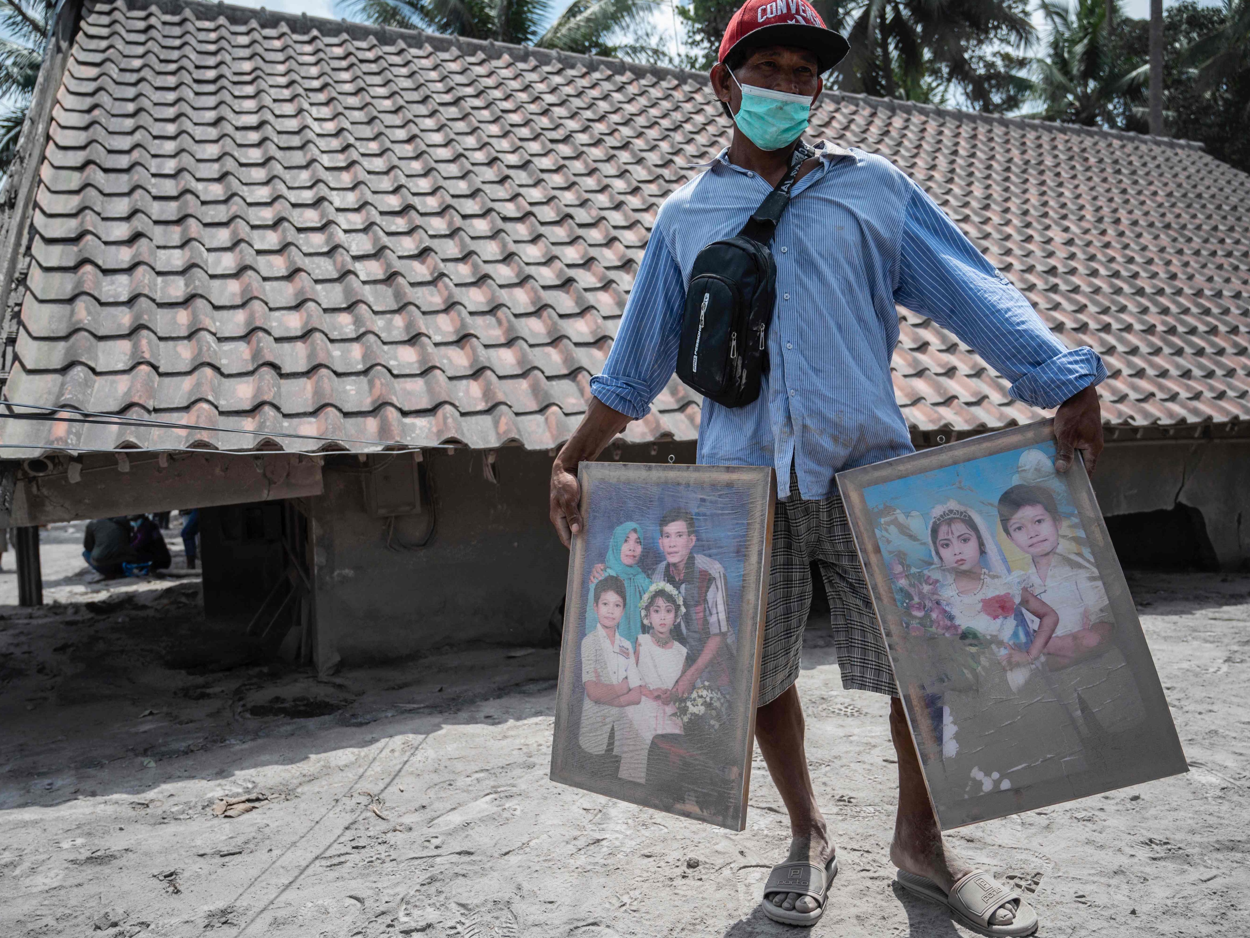 Seorang warga membersihkan potret keluarganya yang berhasil diselamatkan dari rumahnya yang rusak di desa Sumber Wuluh, Lumajang.