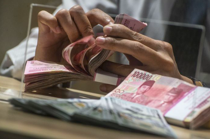 Ilustrasi karyawan bank menghitung uang rupiah.