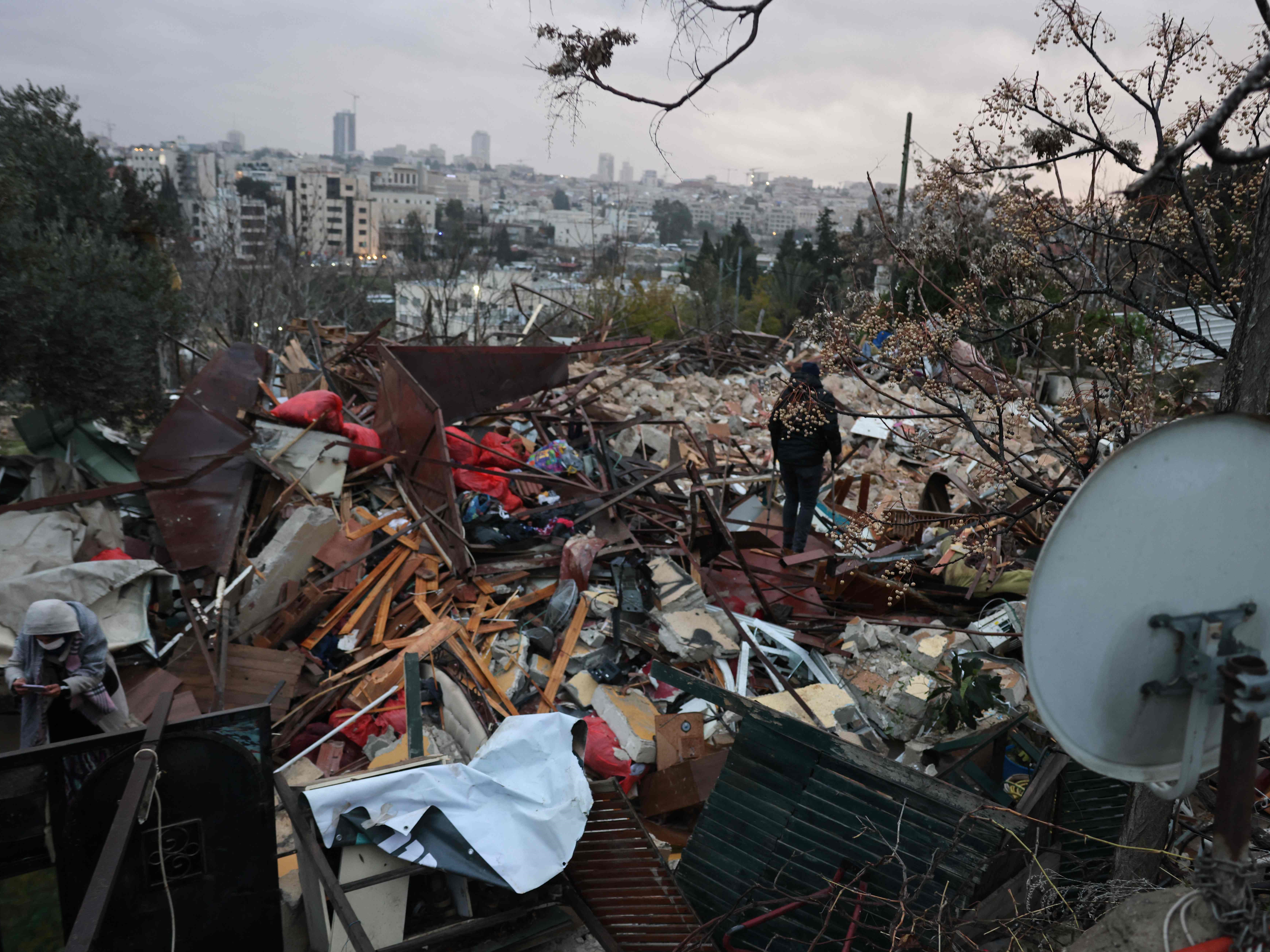 Orang-orang berdiri di atas reruntuhan rumah Palestina yang dihancurkan oleh pasukan Israel di lingkungan Sheik Jarrah, Rabu (19/1).