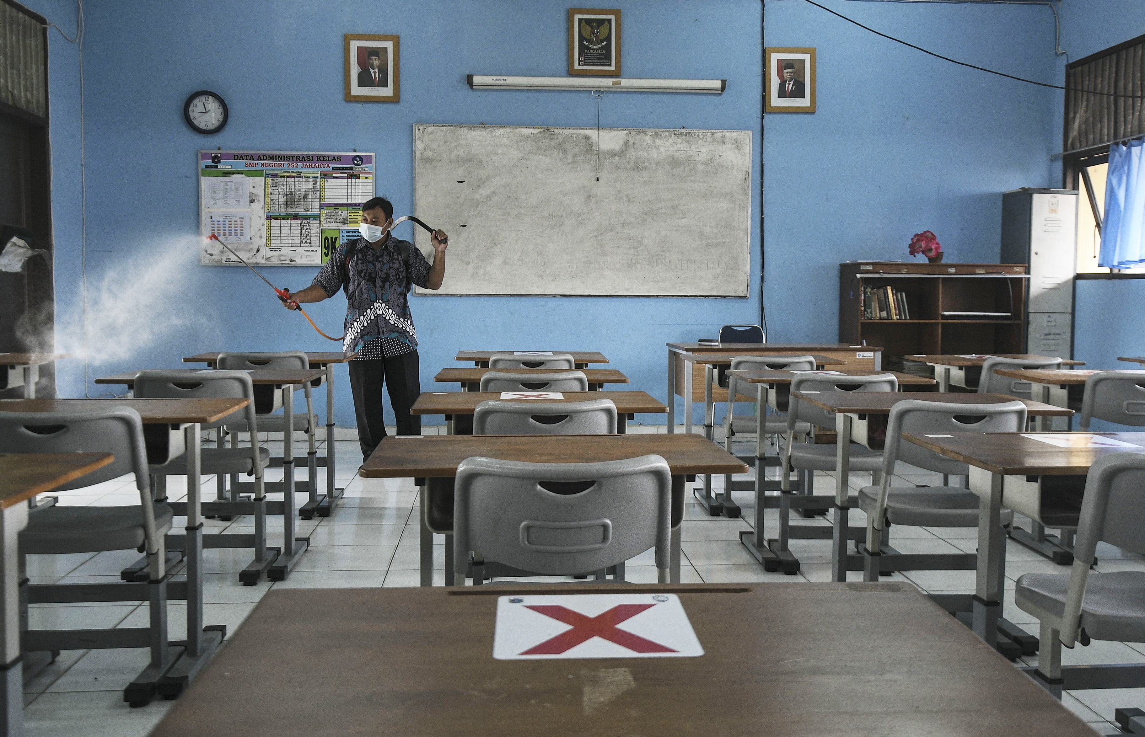 Petugas menyemprotkan disinfektan di ruang kelas SMPN 252, Jakarta Timur, Kamis (13/1/2022), setelah satu siswa positif covid-19.