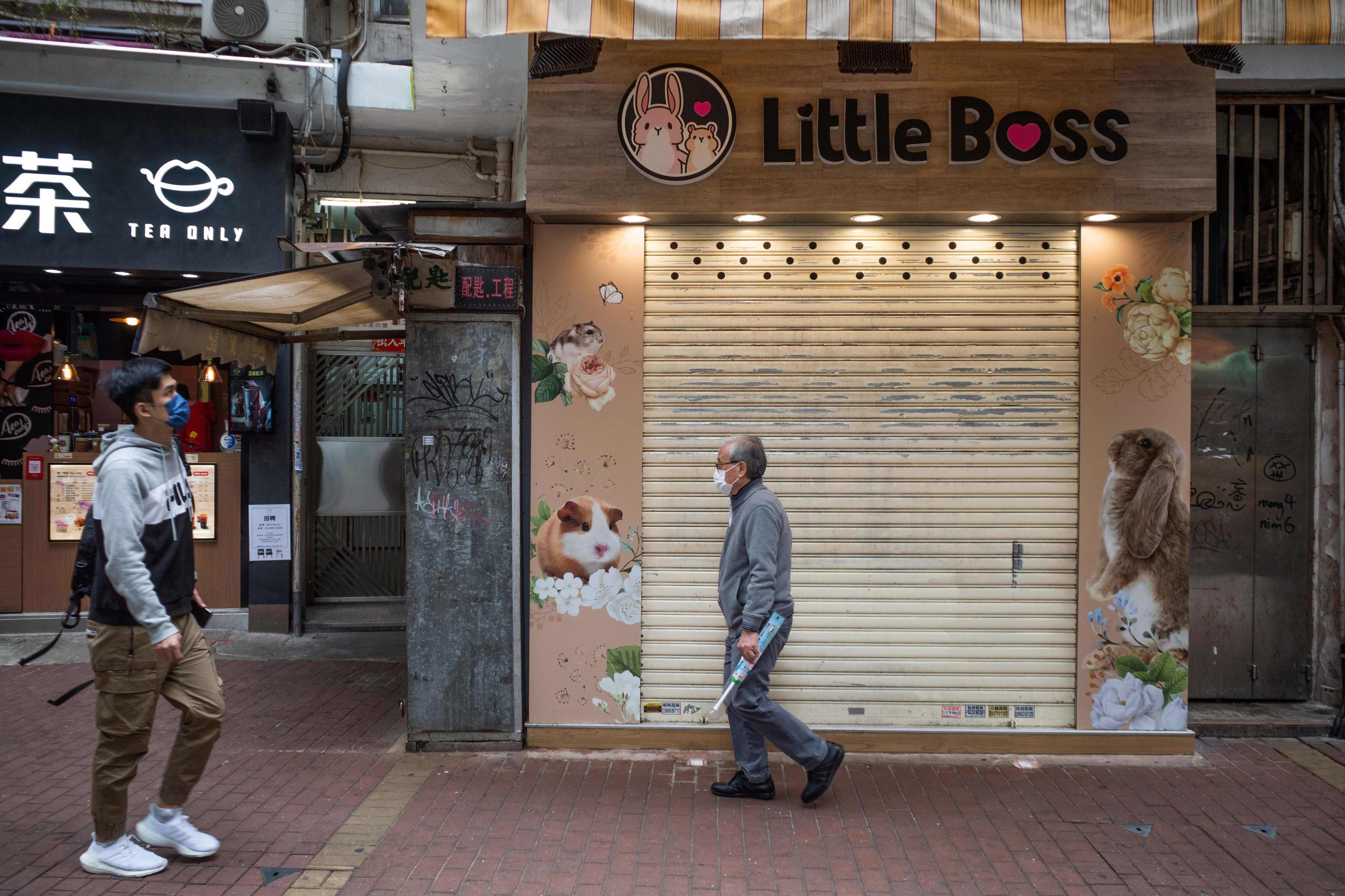 Warga melintas di depan toko binatang peliharaan di Causeway Bay, Hong Kong, tempat seorang karyawan dinyatakan positif covid-19