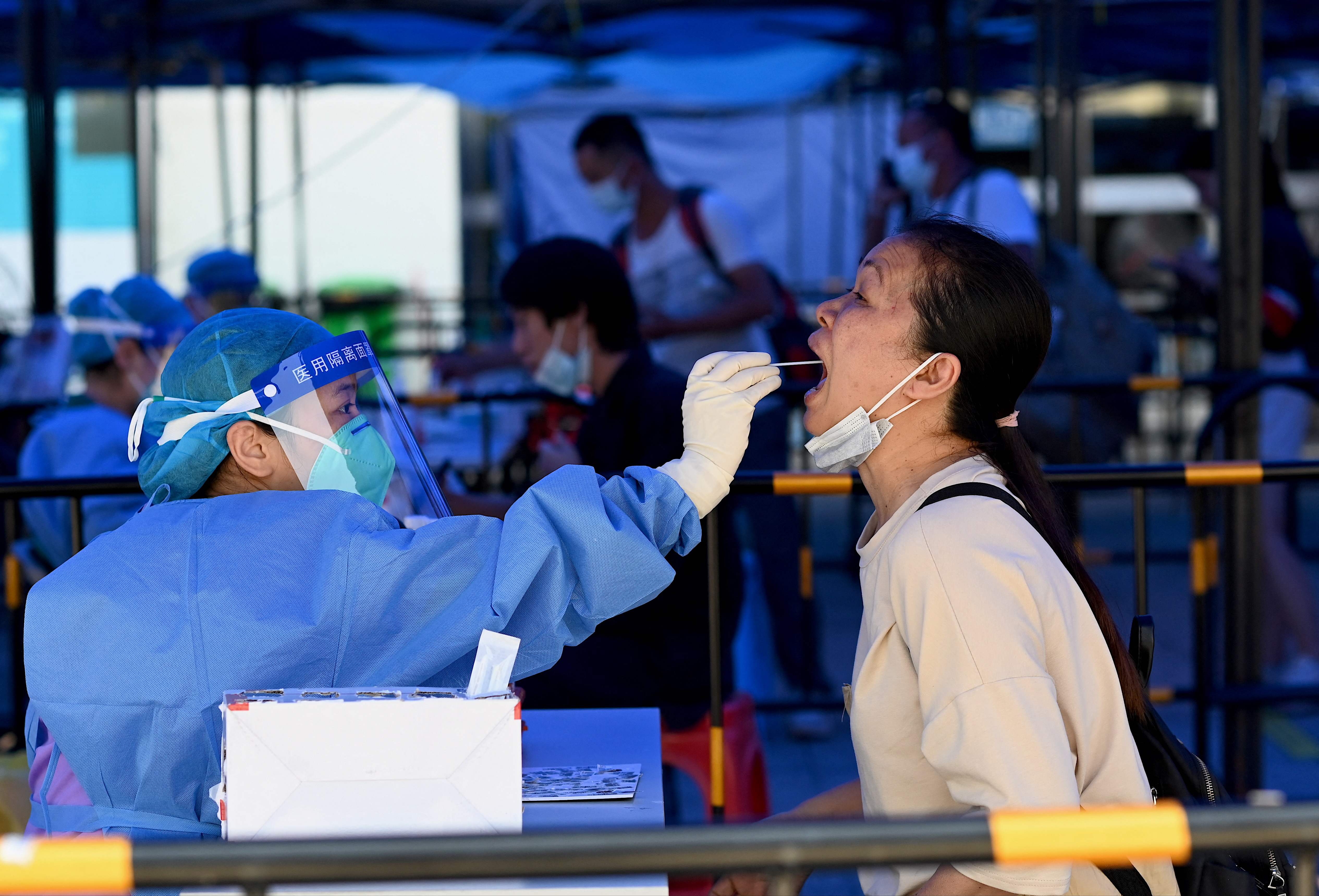 Petugas medis mengambil sampel asam nucleic untuk mengetahui Covid-19 di sebuah stasion kereta di Kota Zhuhai, Tiongkok. 