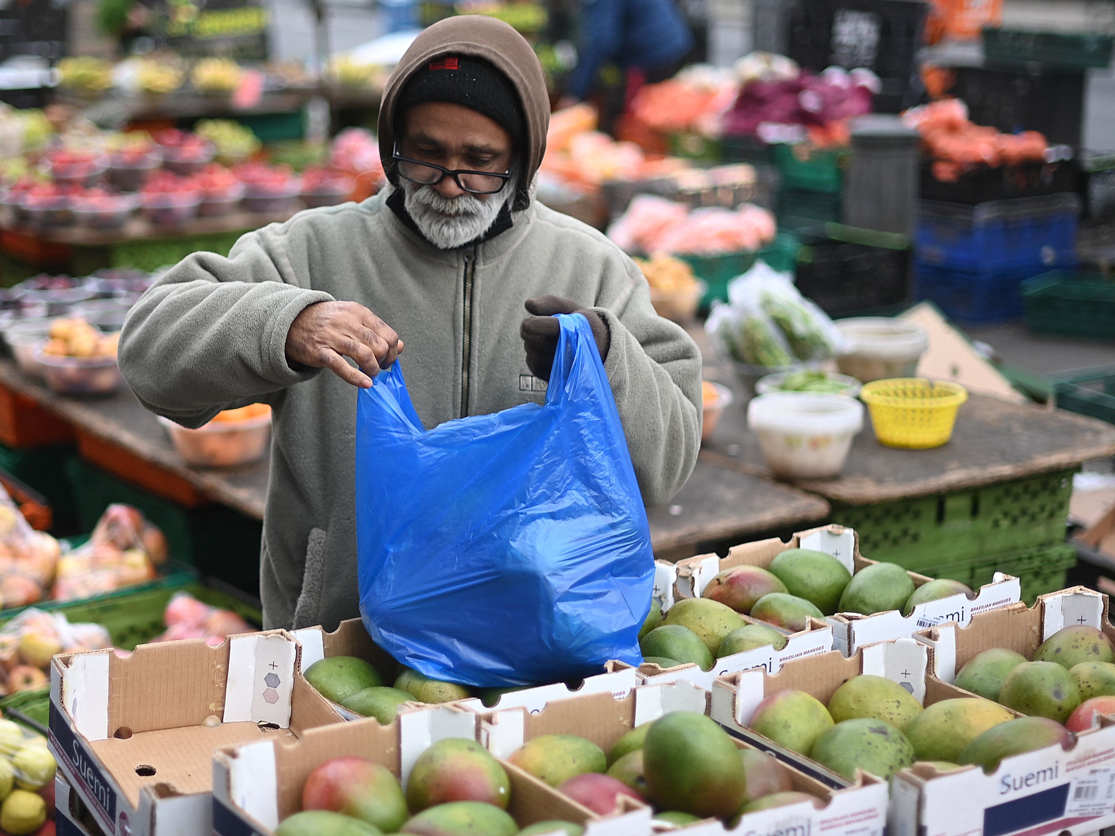 Seorang penjual mengemas produk yang dibeli pelanggan di pasar Whitechapel di London timur pada 10 Januari 2022.