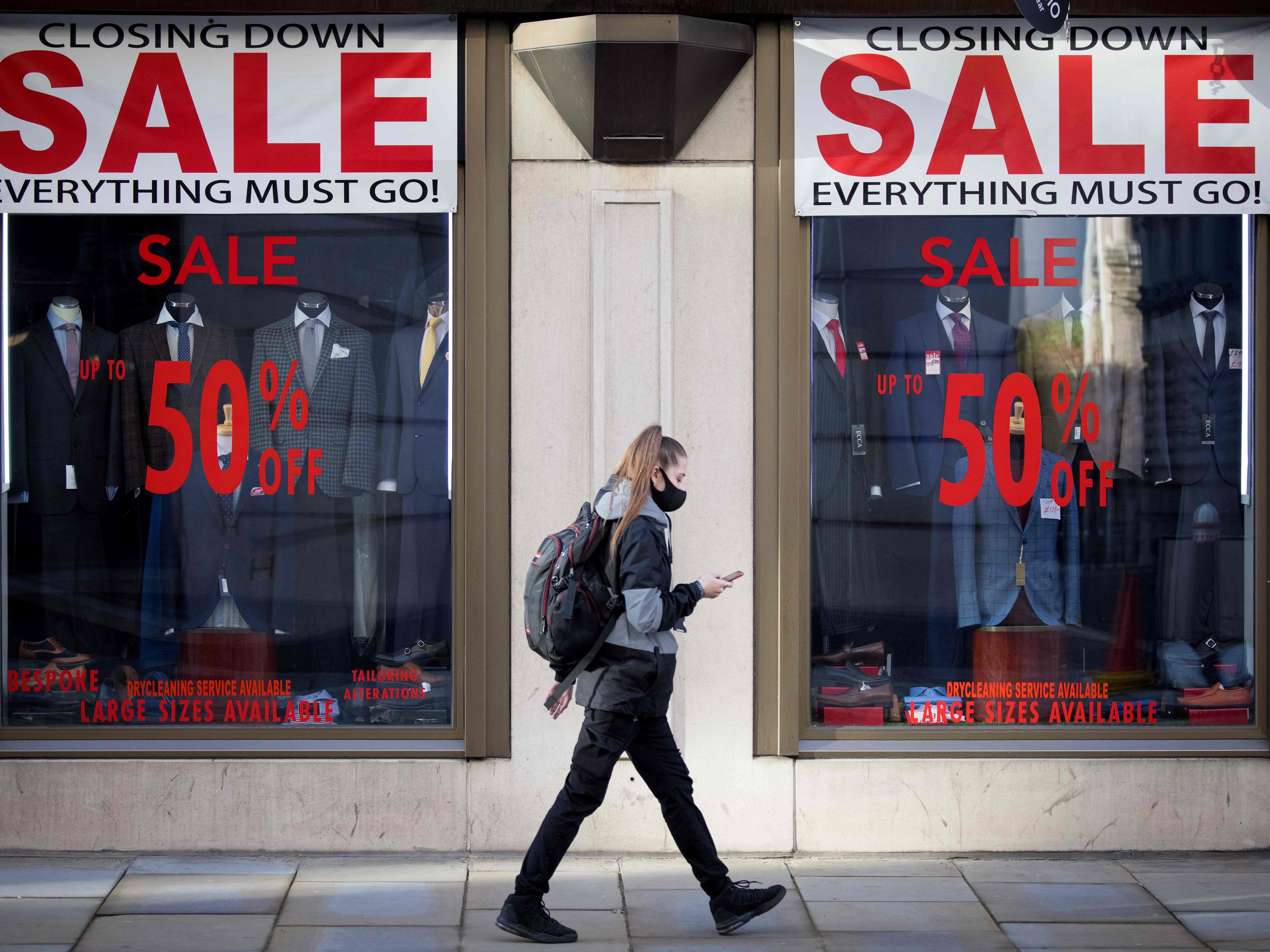 Seorang wanita mengenakan masker berjalan melewati toko di London pada 10 November 2020.