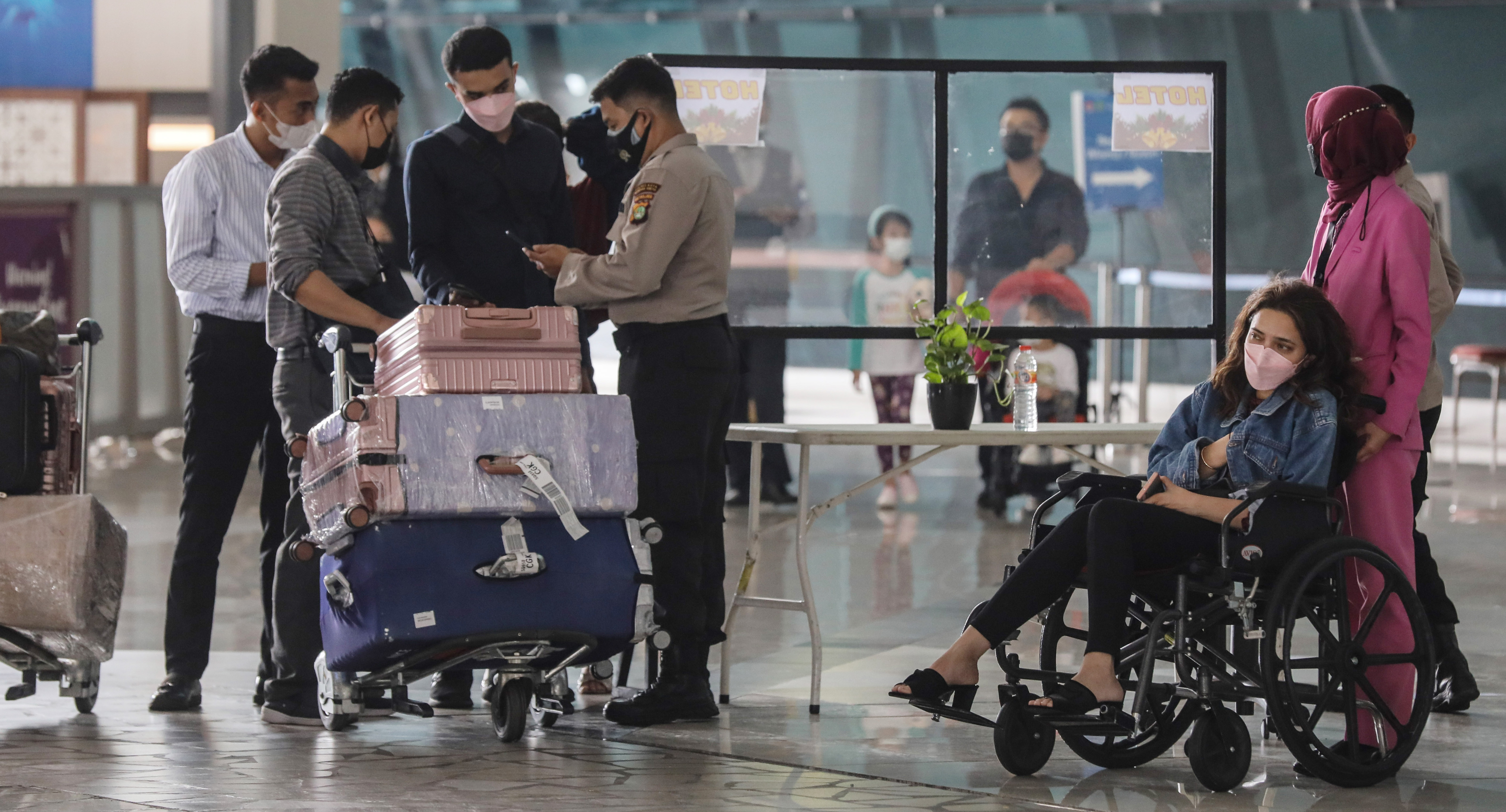 PERKETAT PENGAWASAN : Petugas memeriksa kelengkapan surat wisatawan yang baru tiba dari Abu Dhabi untuk menjalani karantina, Selasa (4/1)