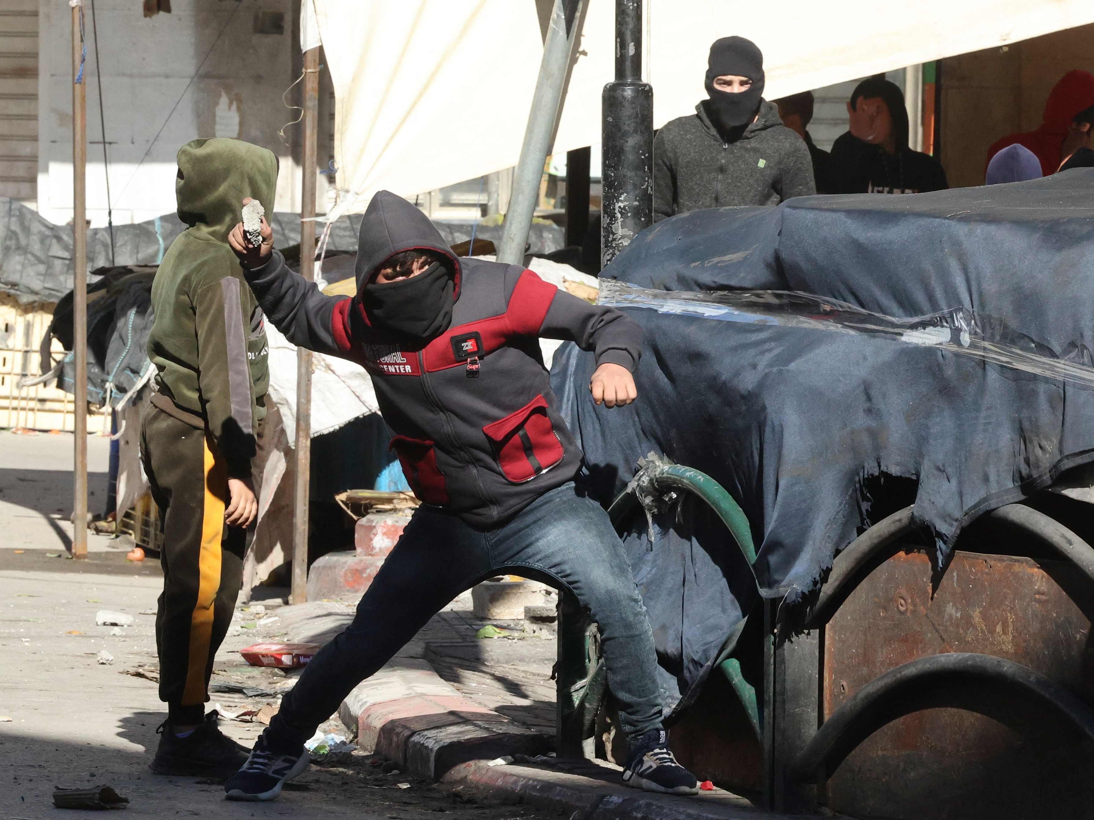 Seorang demonstran Palestina melemparkan batu ke arah pasukan keamanan Israel selama konfrontasi dengan mereka di pusat kota Hebron.