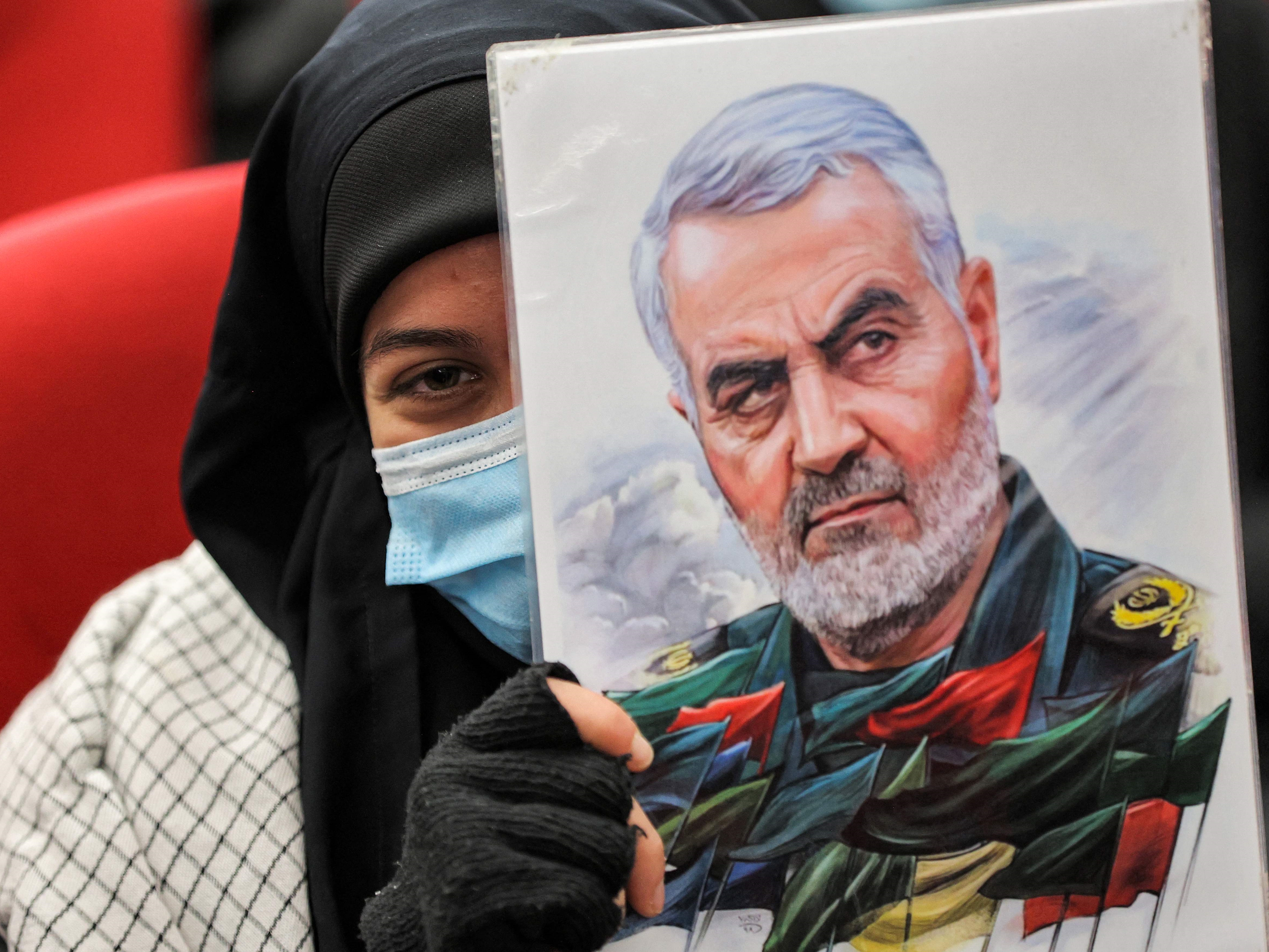 Seorang wanita memegang ilustrasi potret Qasem Soleimani di suatu sekolah, pinggiran selatan ibu kota Libanon, Beirut, 3 Januari 2022.