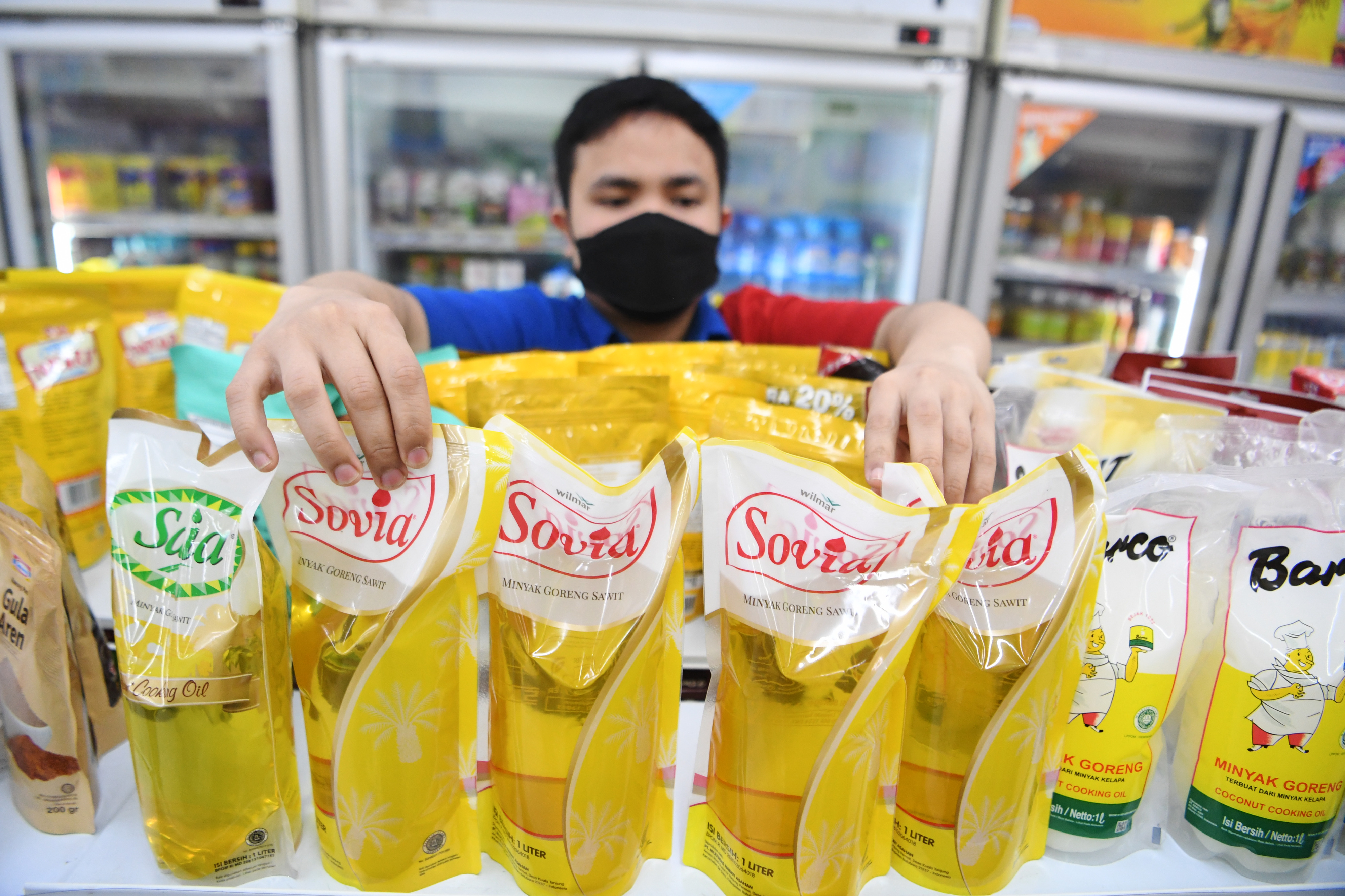 Pekerja menata minyak goreng kemasan yang dijual di salah satu minimarket di Jakarta, Rabu (19/1).