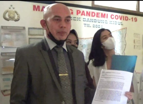 Advokat Ali Akbar Syahrir menunjukkan surat laporan polisi