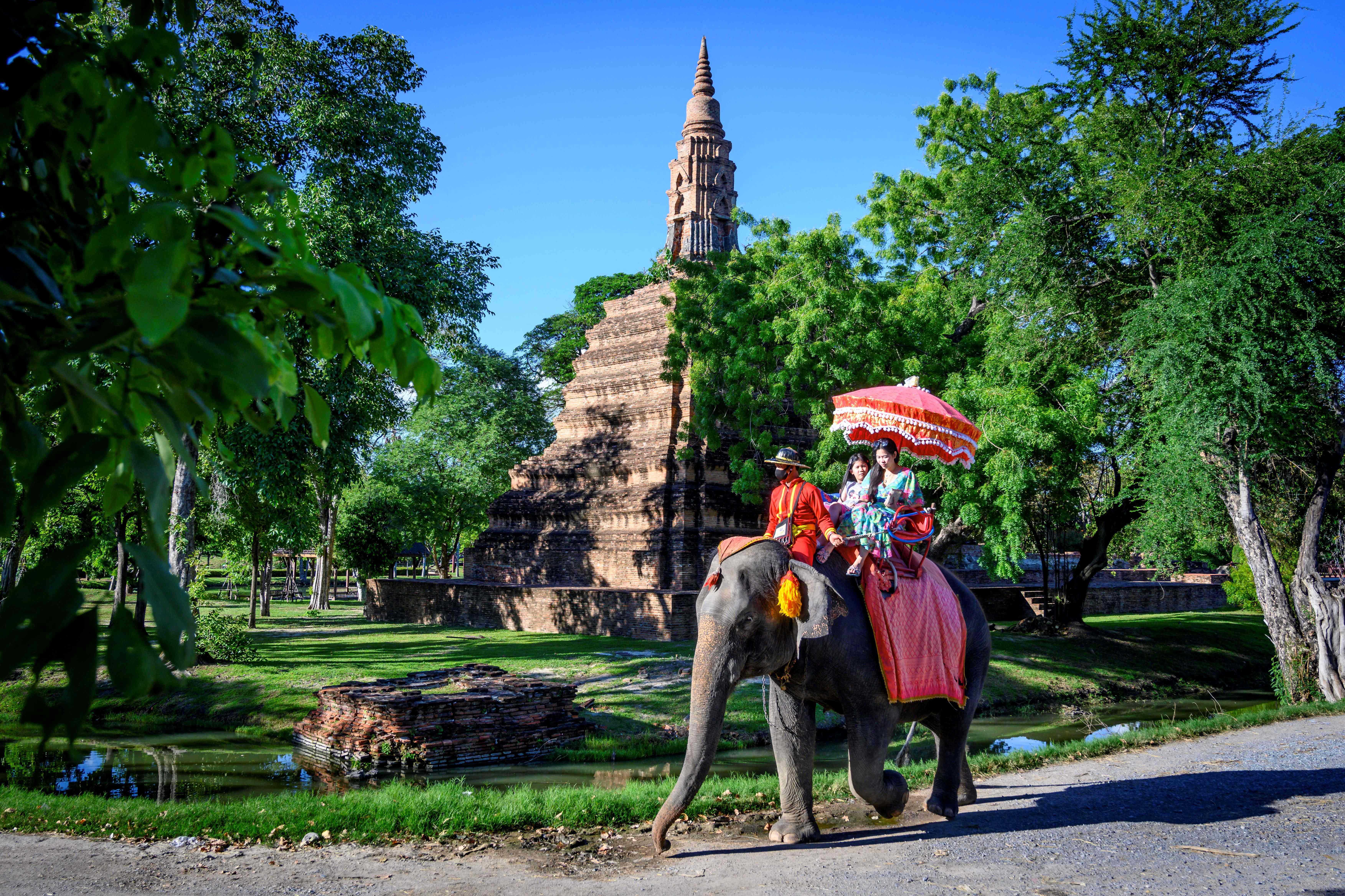 Turis naik gajah di dekat Kuil Budha Ayutthaya, Thailand.