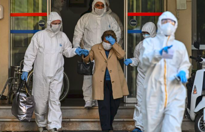 Paramedis Turki yang mengenakan pakaian pelindung membantu pasien yang menunjukkan gejala covid-19 ke ambulans.