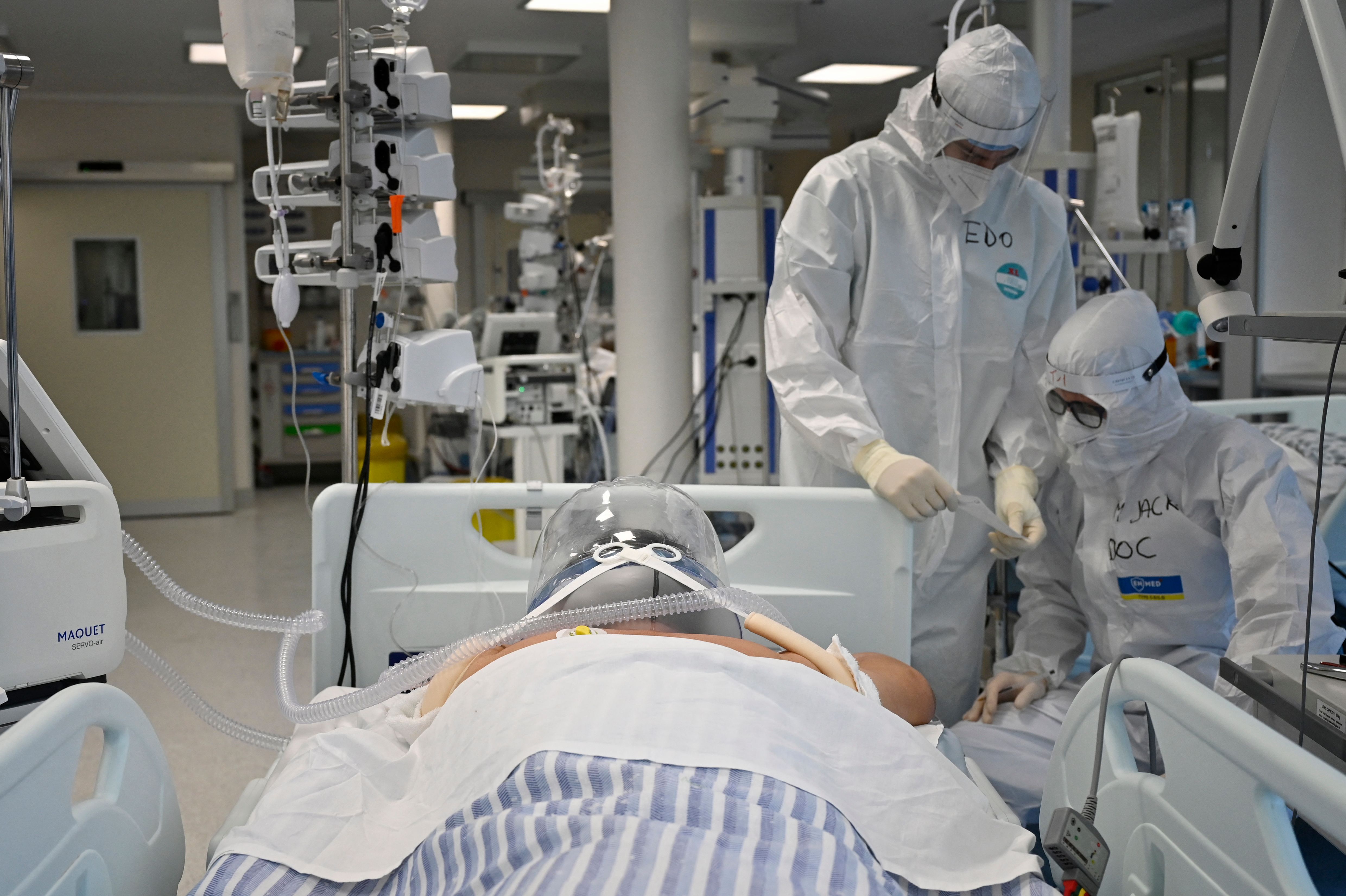 Tenaga kesehatan berdiri di dekat seorang pasienn covid-19 di ICU sebuah rumah sakit di Roma, Italia.