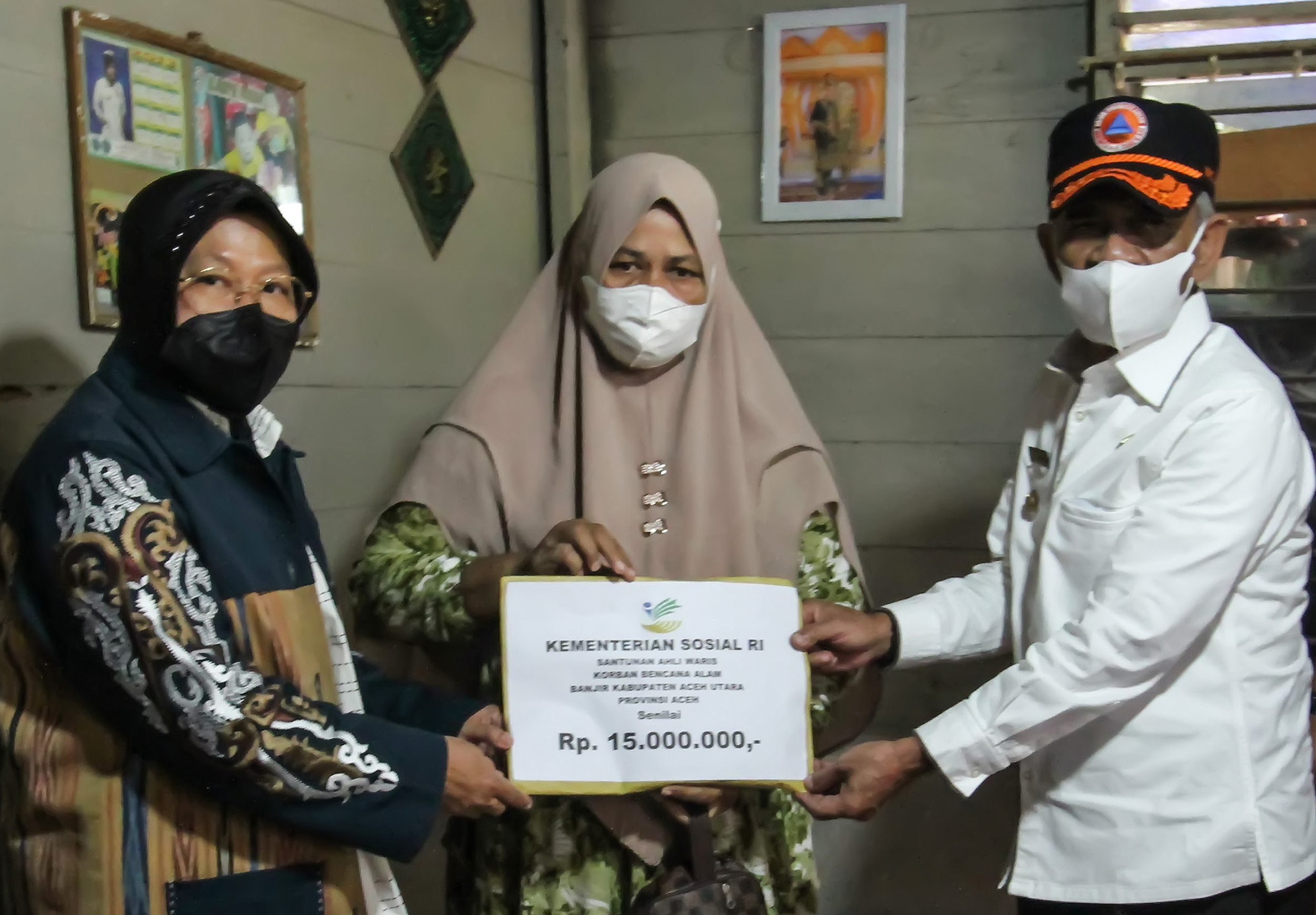 Mensos Tri Rismaharini (kiri) dan Bupati Aceh Utara M Thaeb (kanan) menyerahkan santunan di Desa Meuria, Kecamatan Matang Kuli, Aceh Utara.