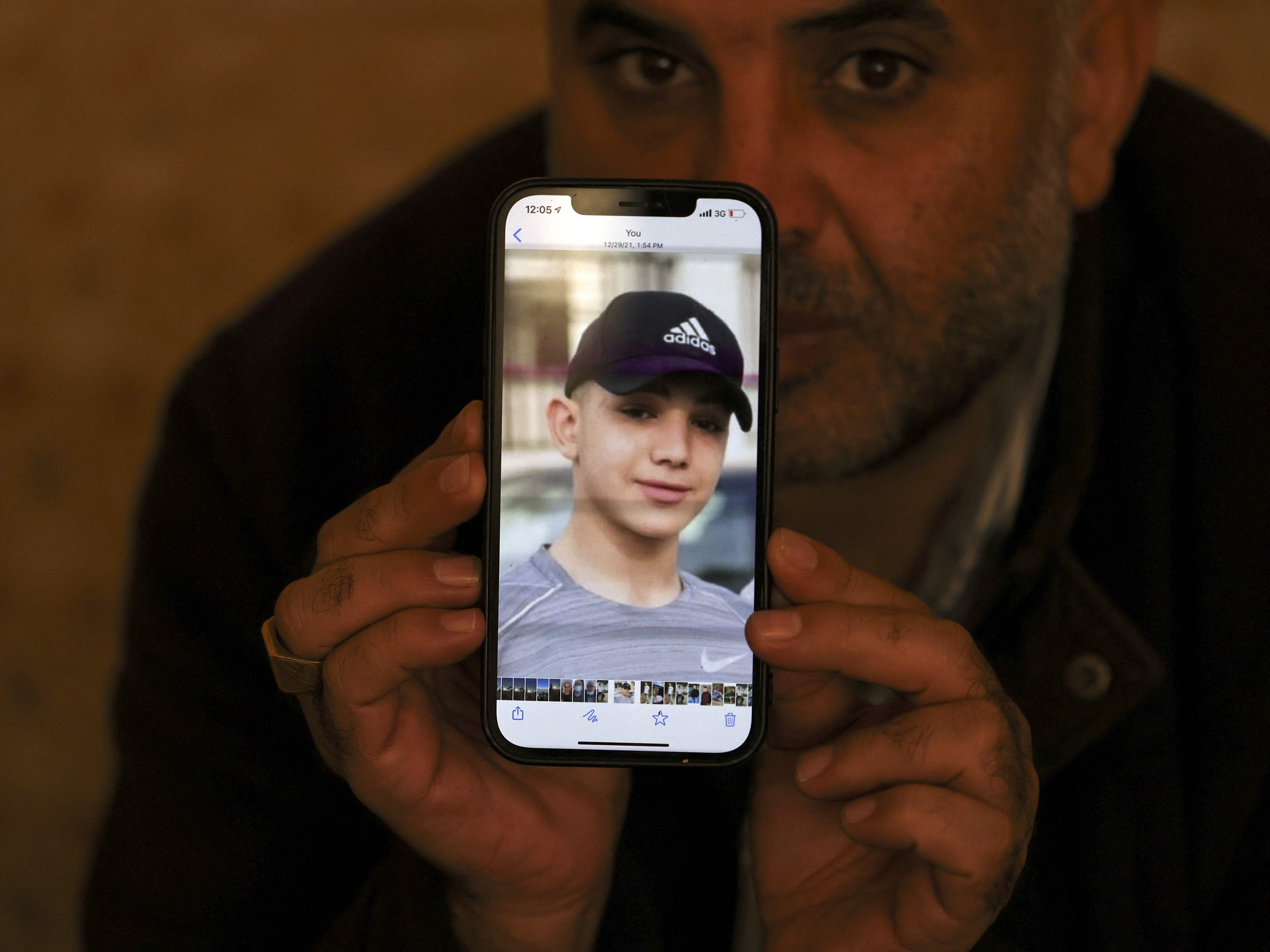 Moammar Nakhleh, ayah dari Amal, menunjukkan foto putranya lewat teleponnya, di kamp pengungsi Jalazun, Tepi Barat, Sabtu (8/1).