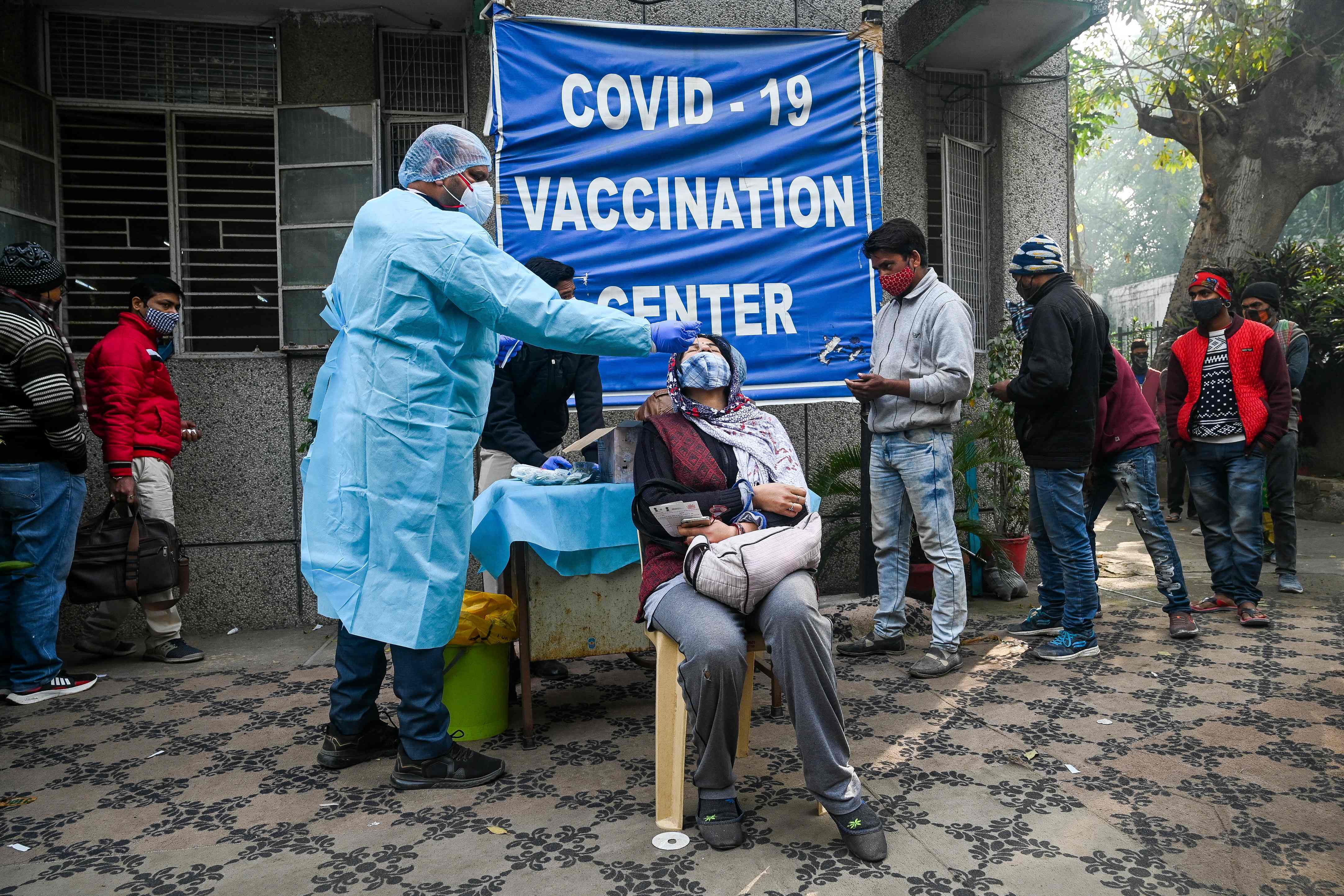 Petugas medis melakukan tes PCR terhadap warga di pusat vaksinasi Covid-19 di New Dehli, Inida, Selasa (4/1).